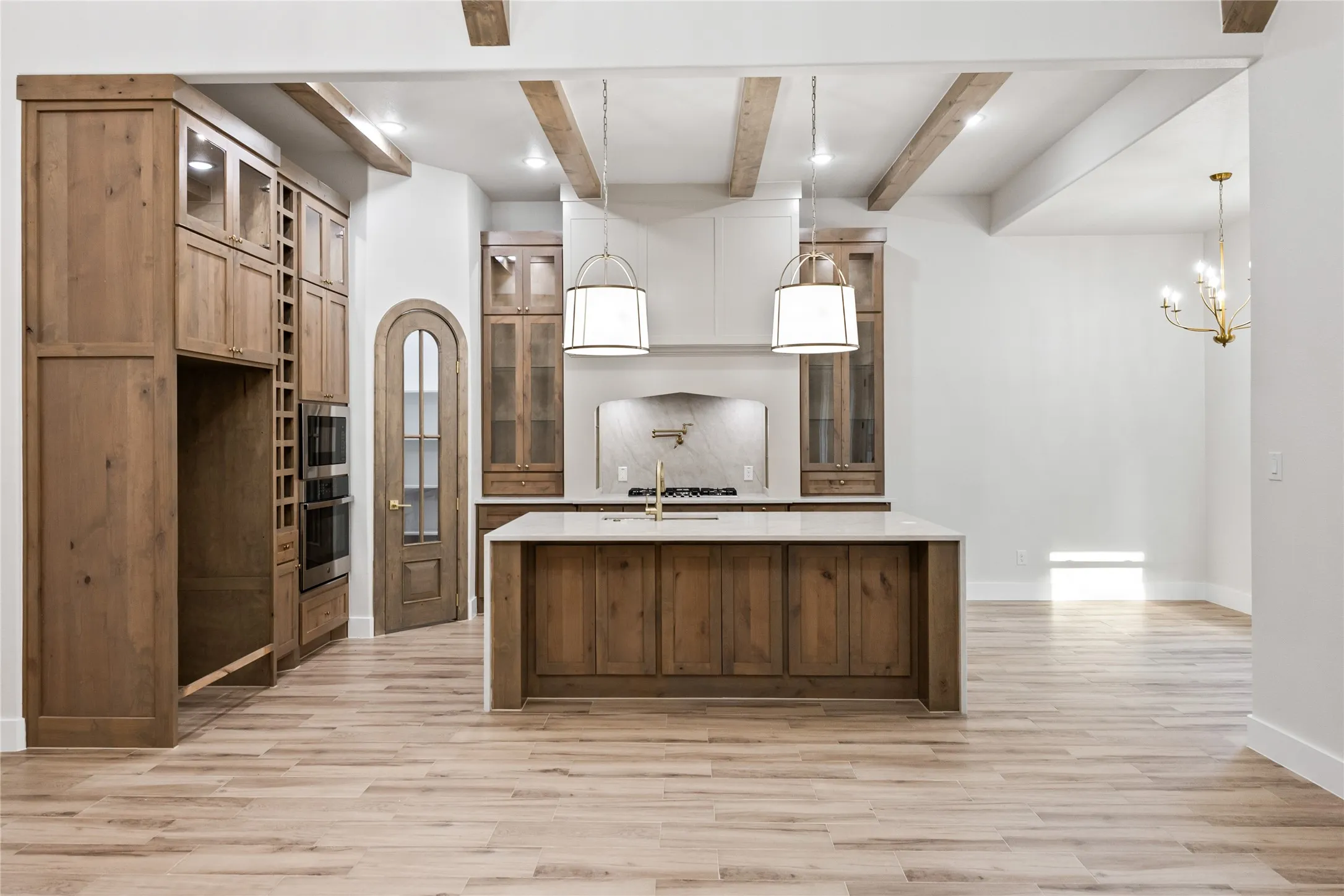 Kitchen featuring wood-finish cabinetry, a central island with countertop, and integrated double ovens