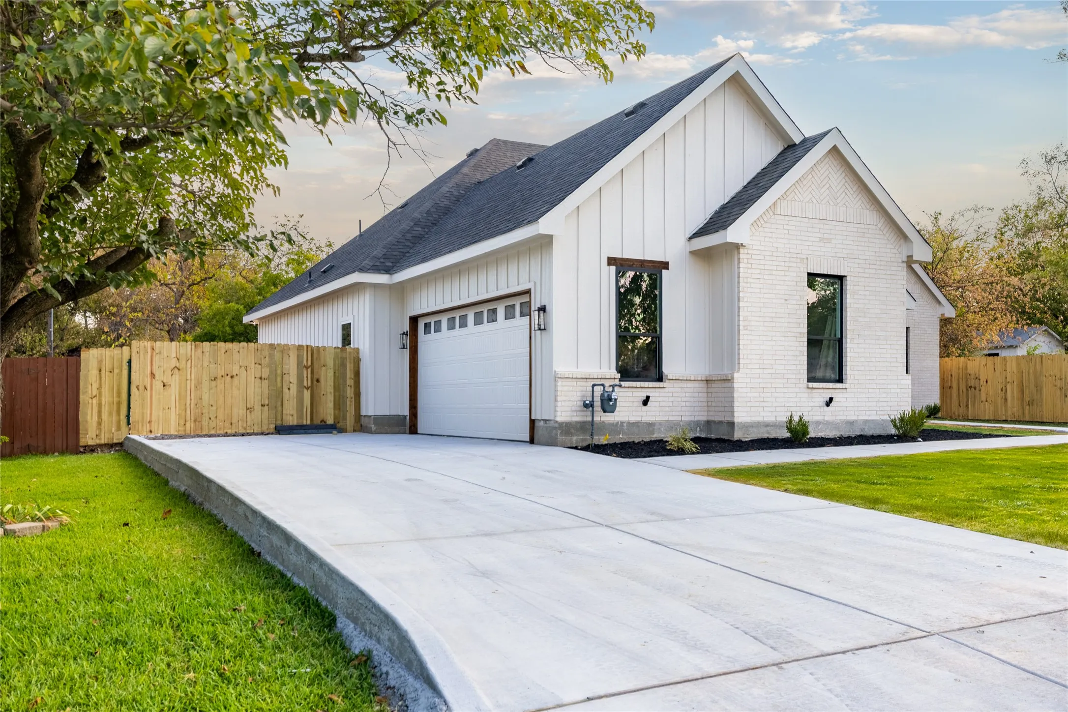 White brick and vertical siding exterior with a dark shingle roof