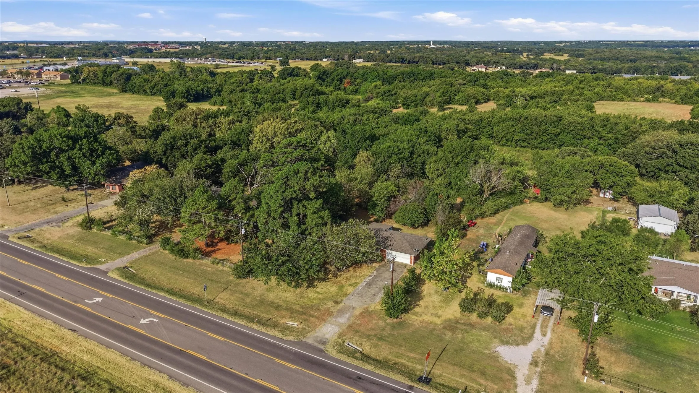Expansive property featuring mature trees and a paved road frontage
