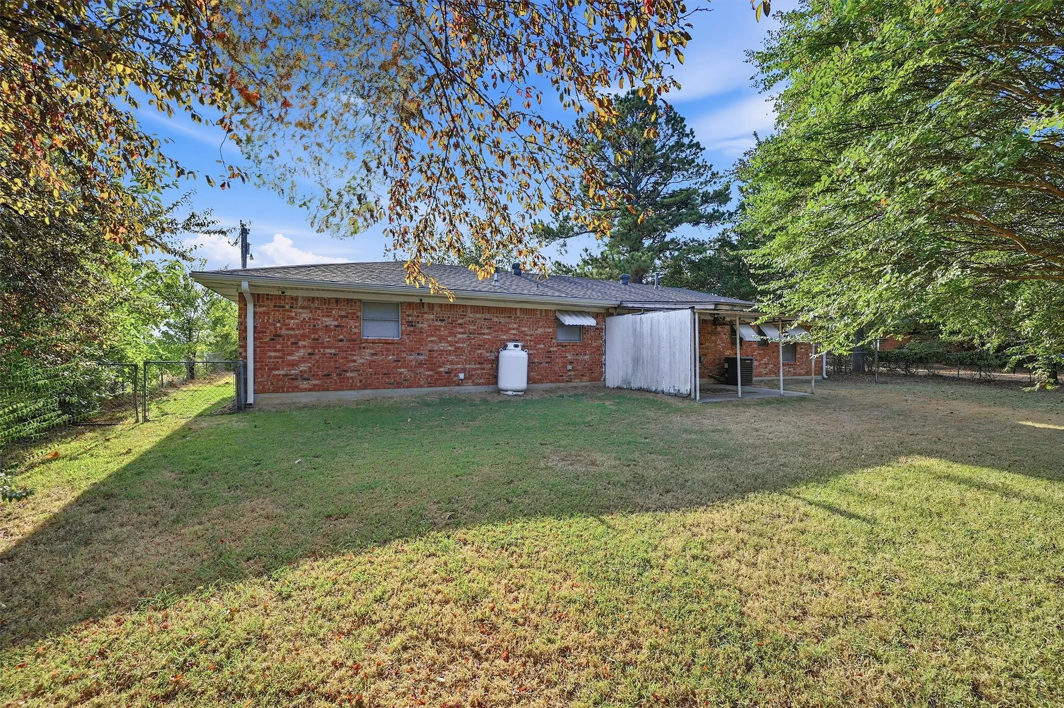 Brick exterior with a covered patio area and mature trees