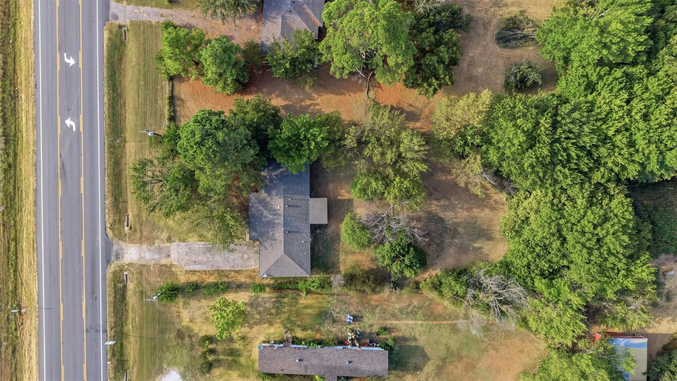 Aerial perspective showcasing the property's expansive lot, mature trees, and direct road frontage
