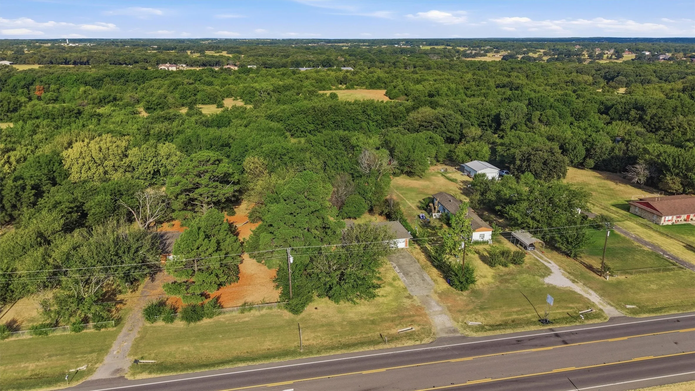 Extensive wooded acreage with a main road frontage, featuring multiple structures and clearings
