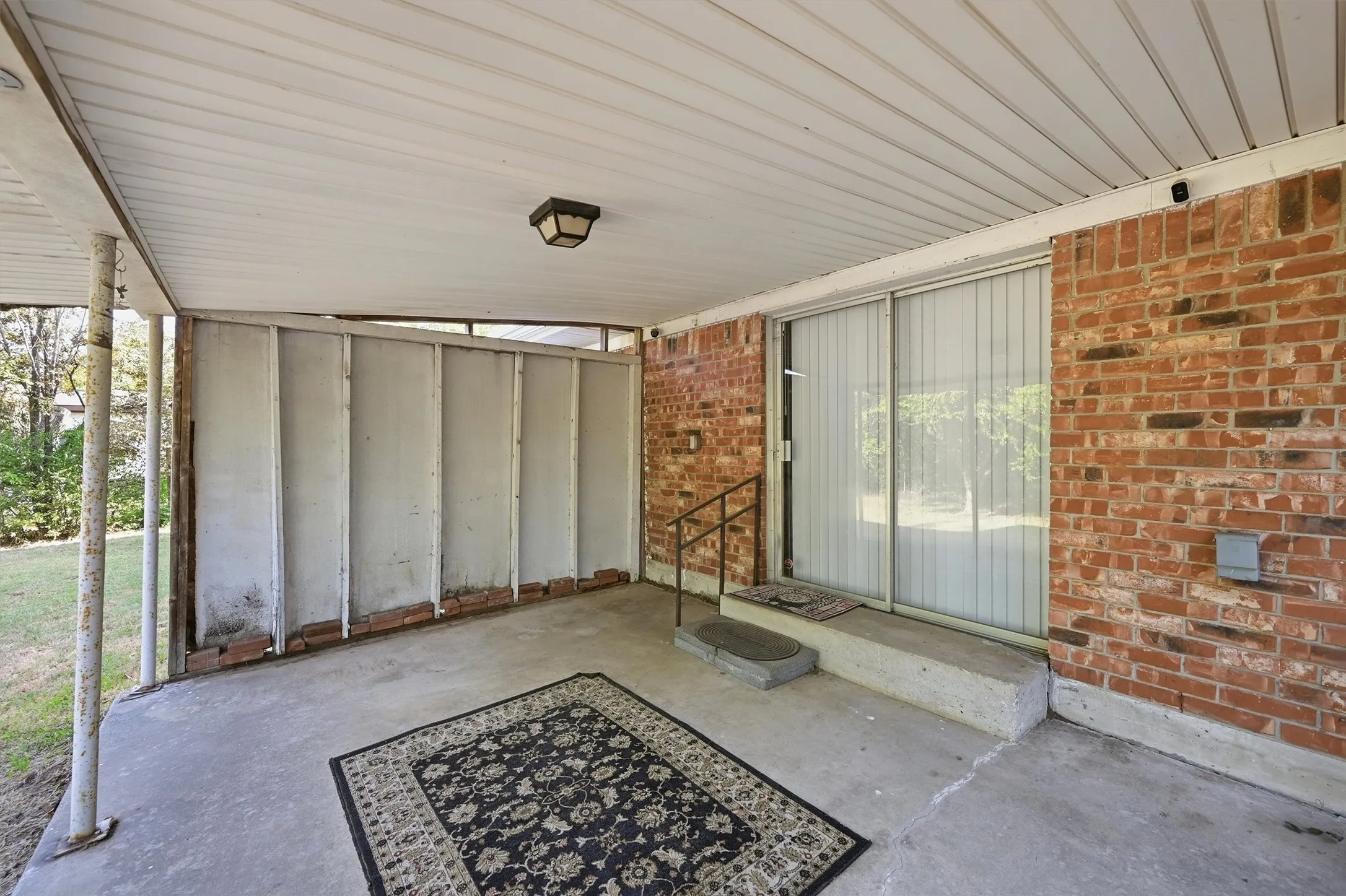 Covered patio featuring a concrete floor, brick wall construction, and a sliding glass door