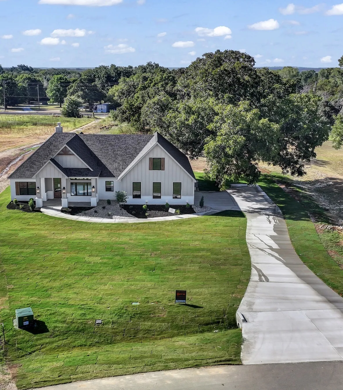 Modern farmhouse exterior with board and batten siding, dark shingle roof, and wood-toned window shutters