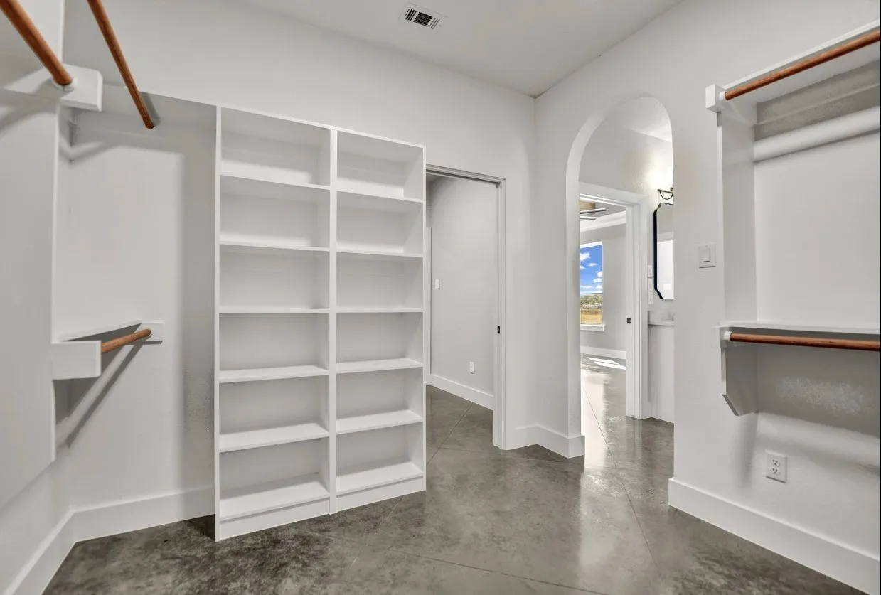 Expansive closet featuring built-in shelving, hanging rods, and polished concrete flooring