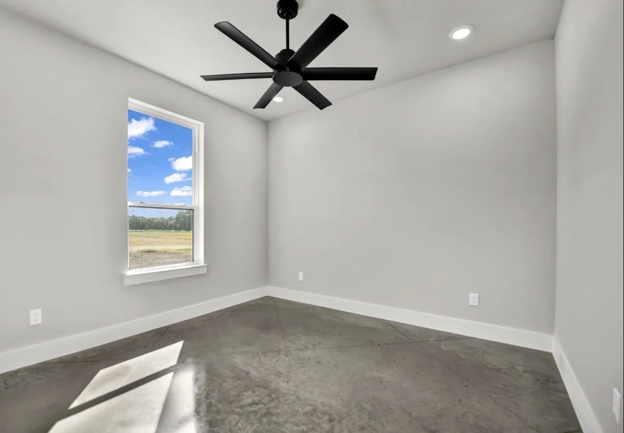 High ceilings with recessed lighting, modern matte black ceiling fan, concrete flooring, and a large window