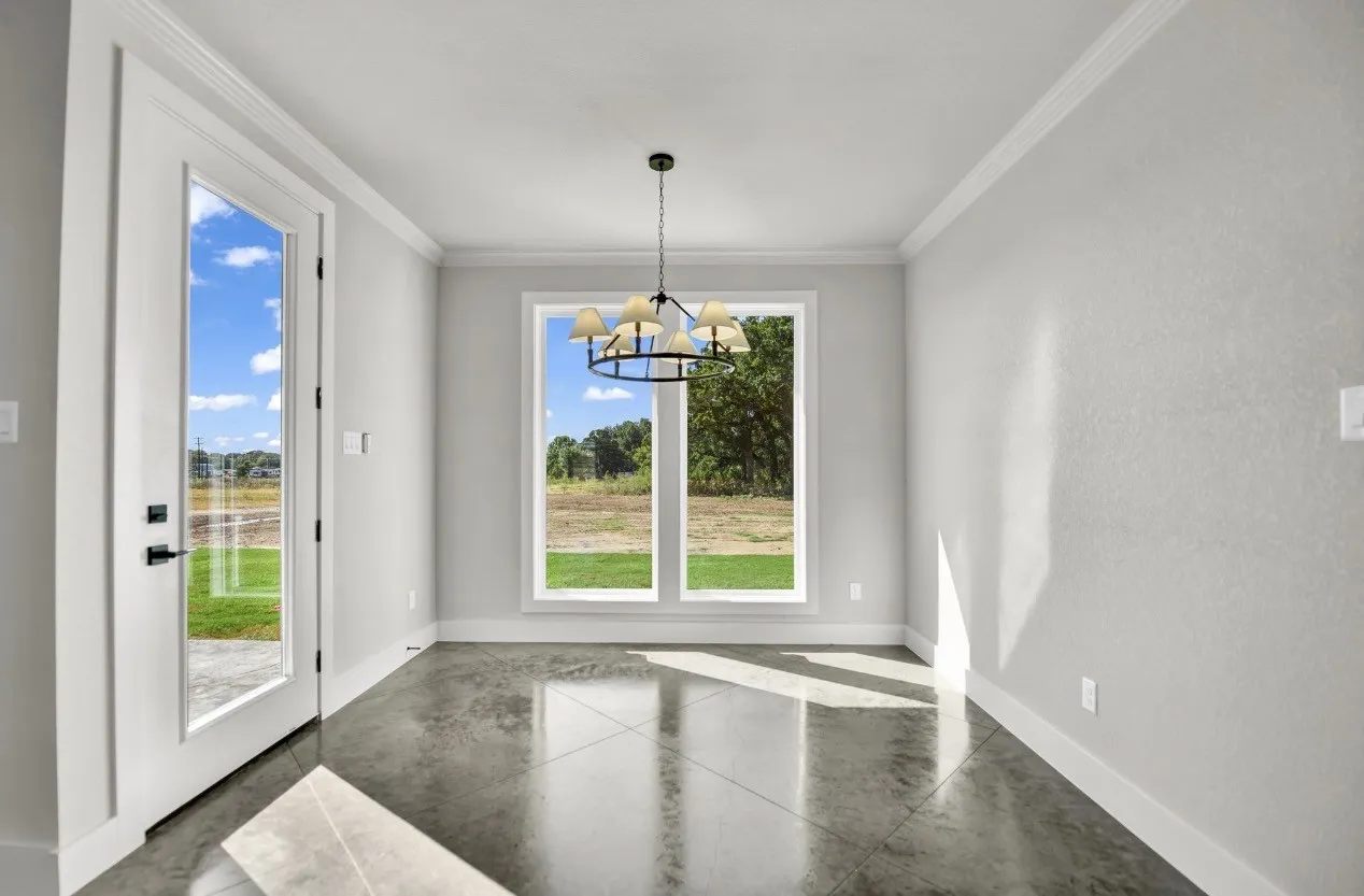 Polished concrete flooring, full-light exterior door with matte black hardware, and an iron chandelier with fabric shades