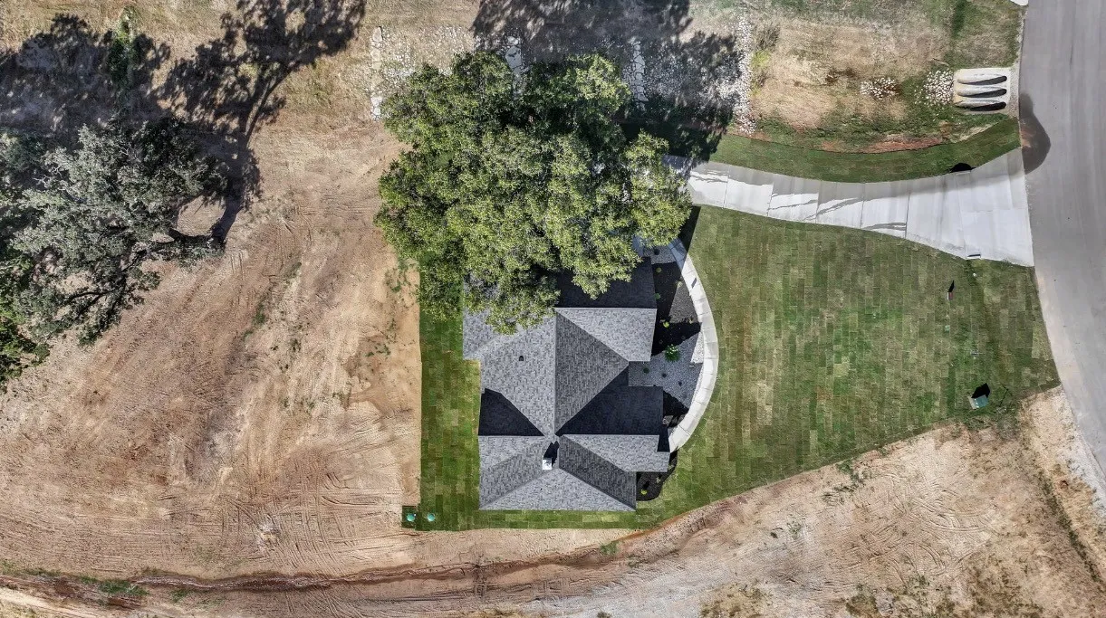 New construction with a shingled roof, manicured lawn, and a concrete driveway