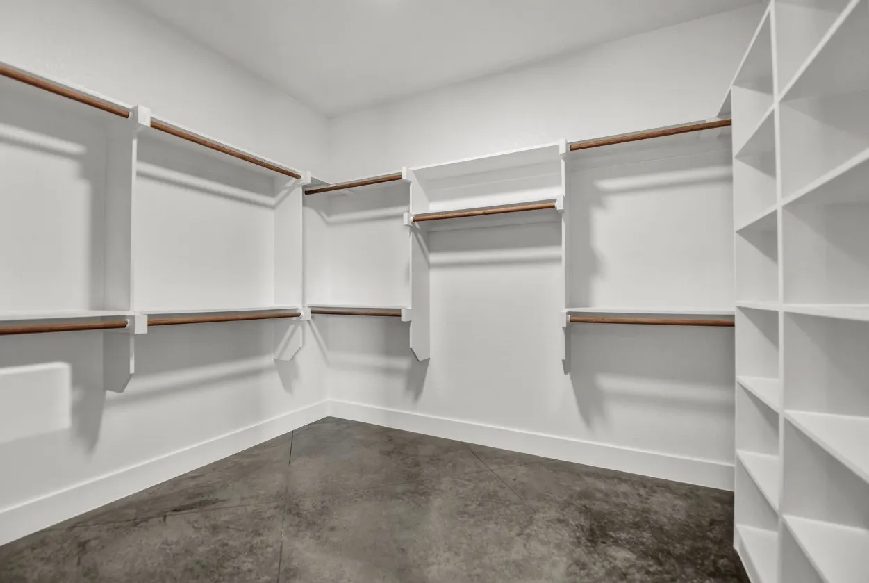 Spacious walk-in closet with white shelving and integrated hanging rods