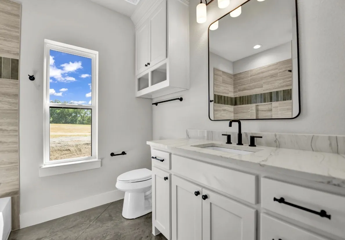 White shaker-style vanity with a stone countertop, undermount sink, and matte black fixtures