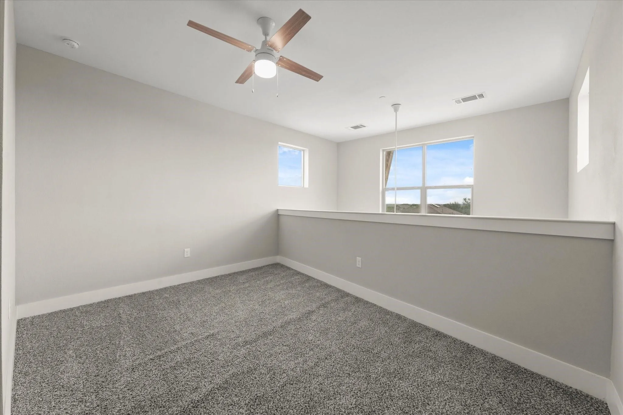 Carpeted loft space featuring an overhead ceiling fan with wood-finish blades, recessed lighting, and multiple windows