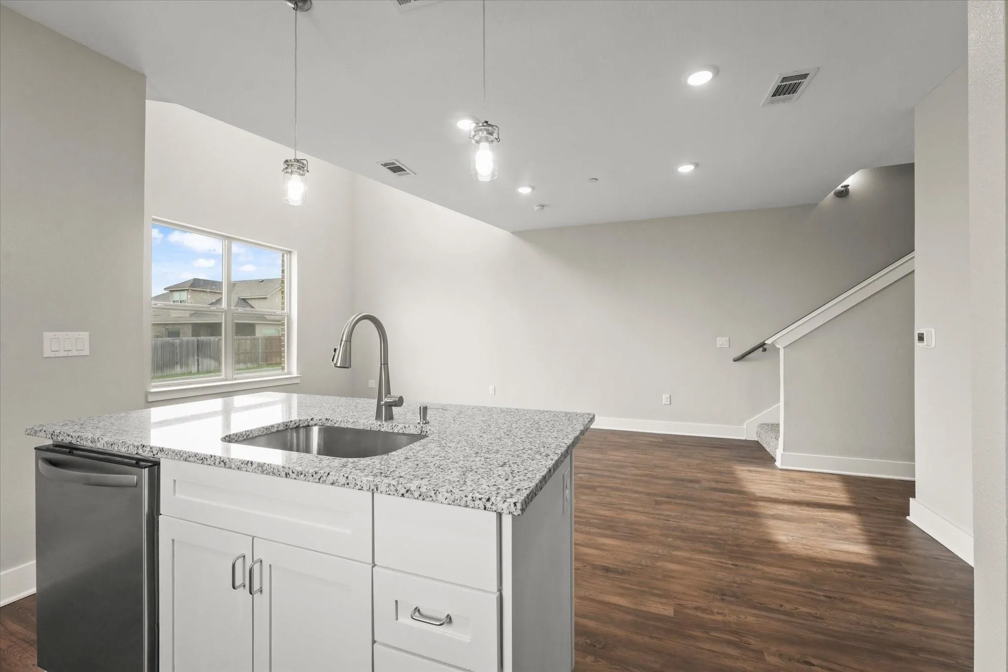 Kitchen island with granite countertop, integrated stainless steel sink, and dishwasher