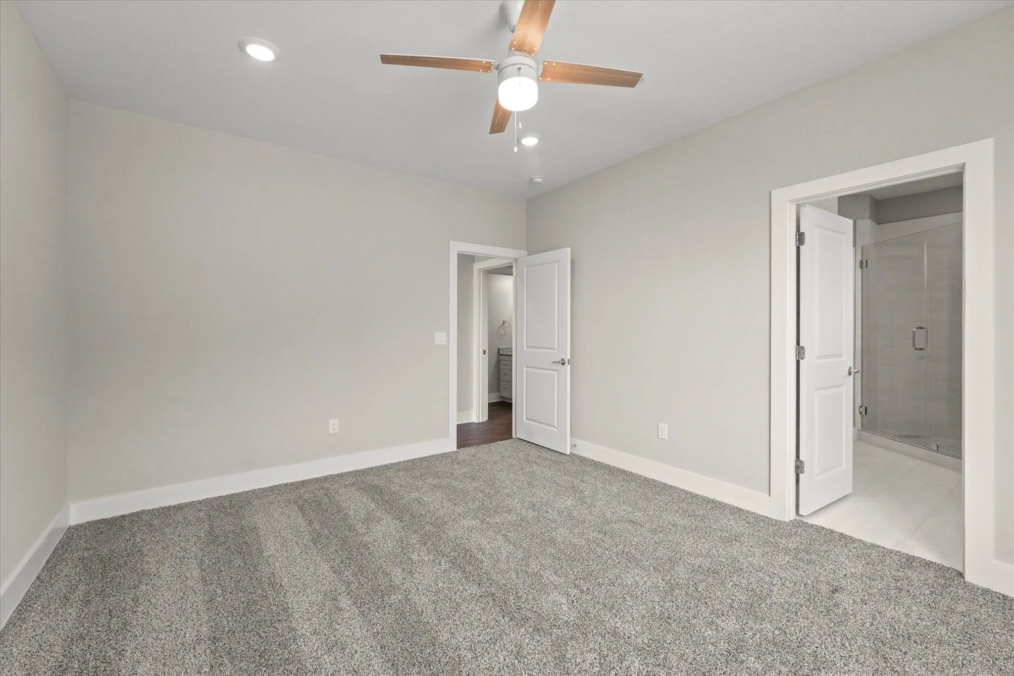 Recessed lighting, ceiling fan with wood-finish blades, and neutral-toned carpeting