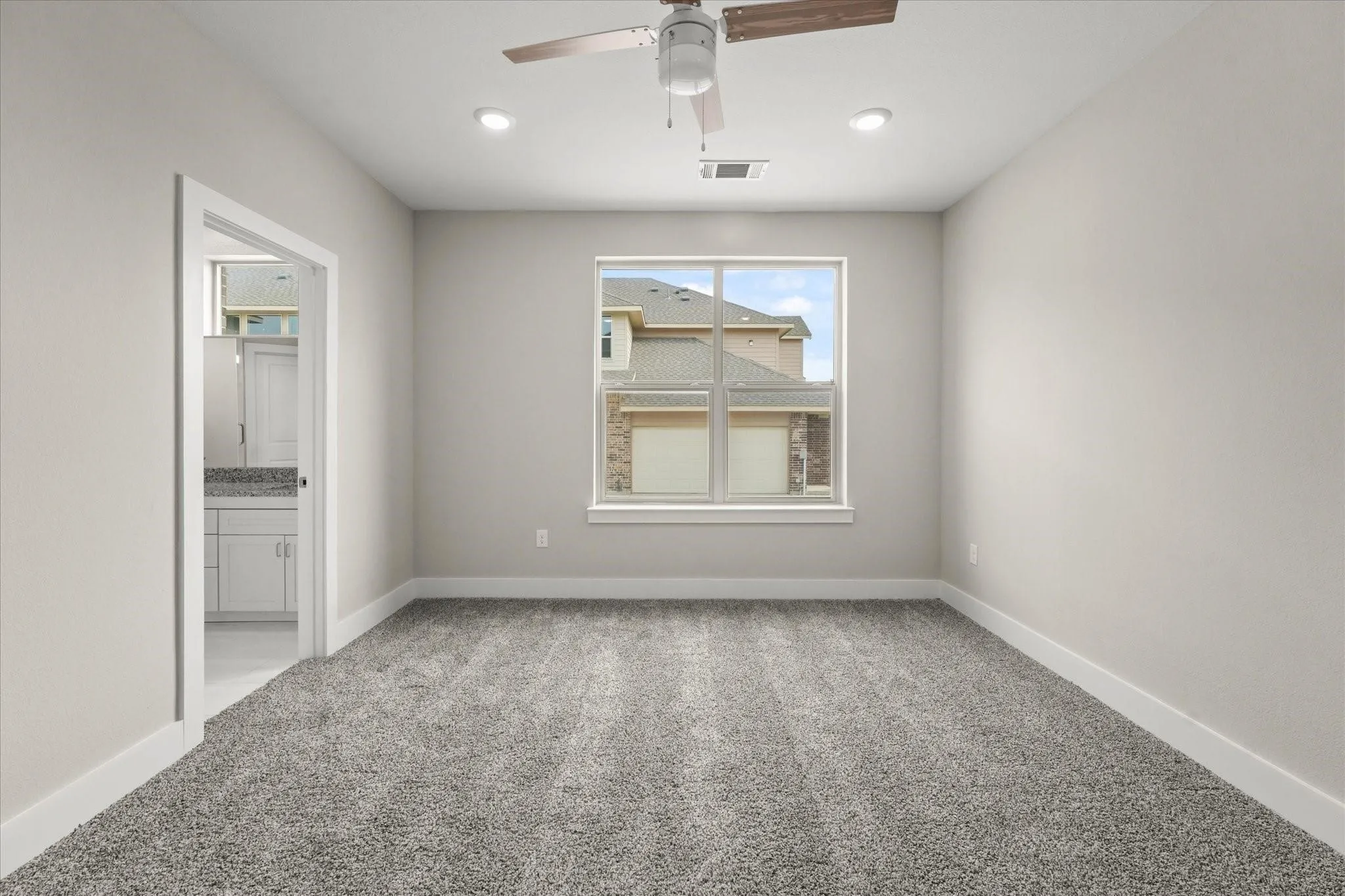 Neutral tone walls, ceiling fan, recessed lighting, gray carpeting, and a white framed window