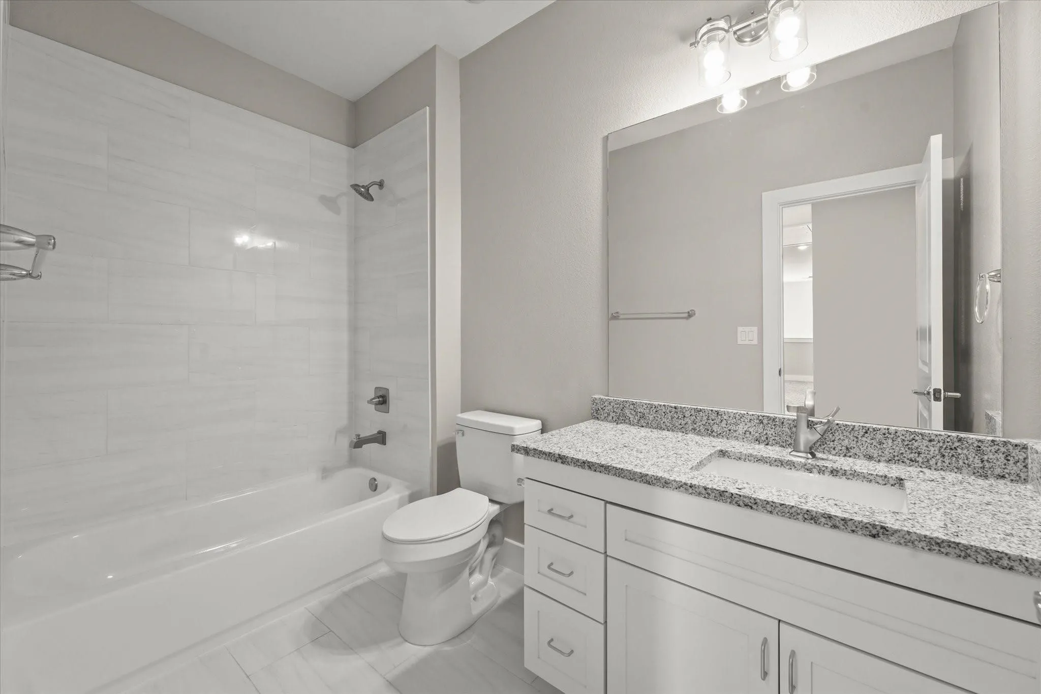 Bathtub with subway tile surround, single vanity with light-toned countertop, integrated sink, and chrome fixtures