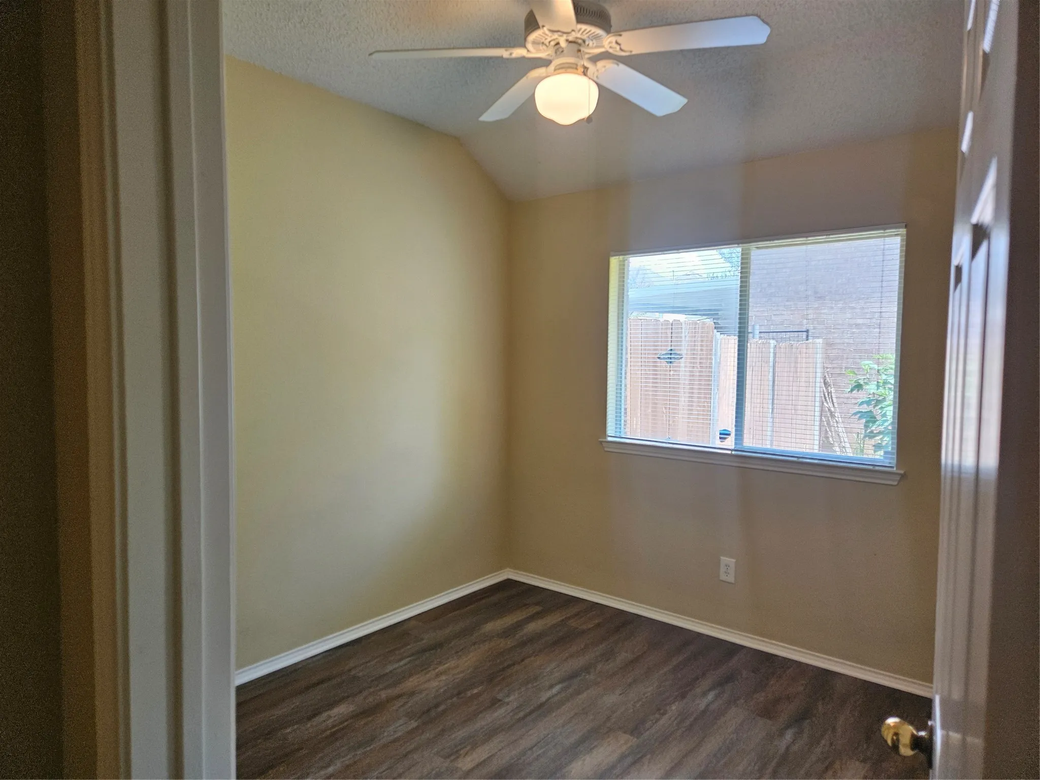 Room featuring wood-finish flooring, a ceiling fan, and a window with blinds