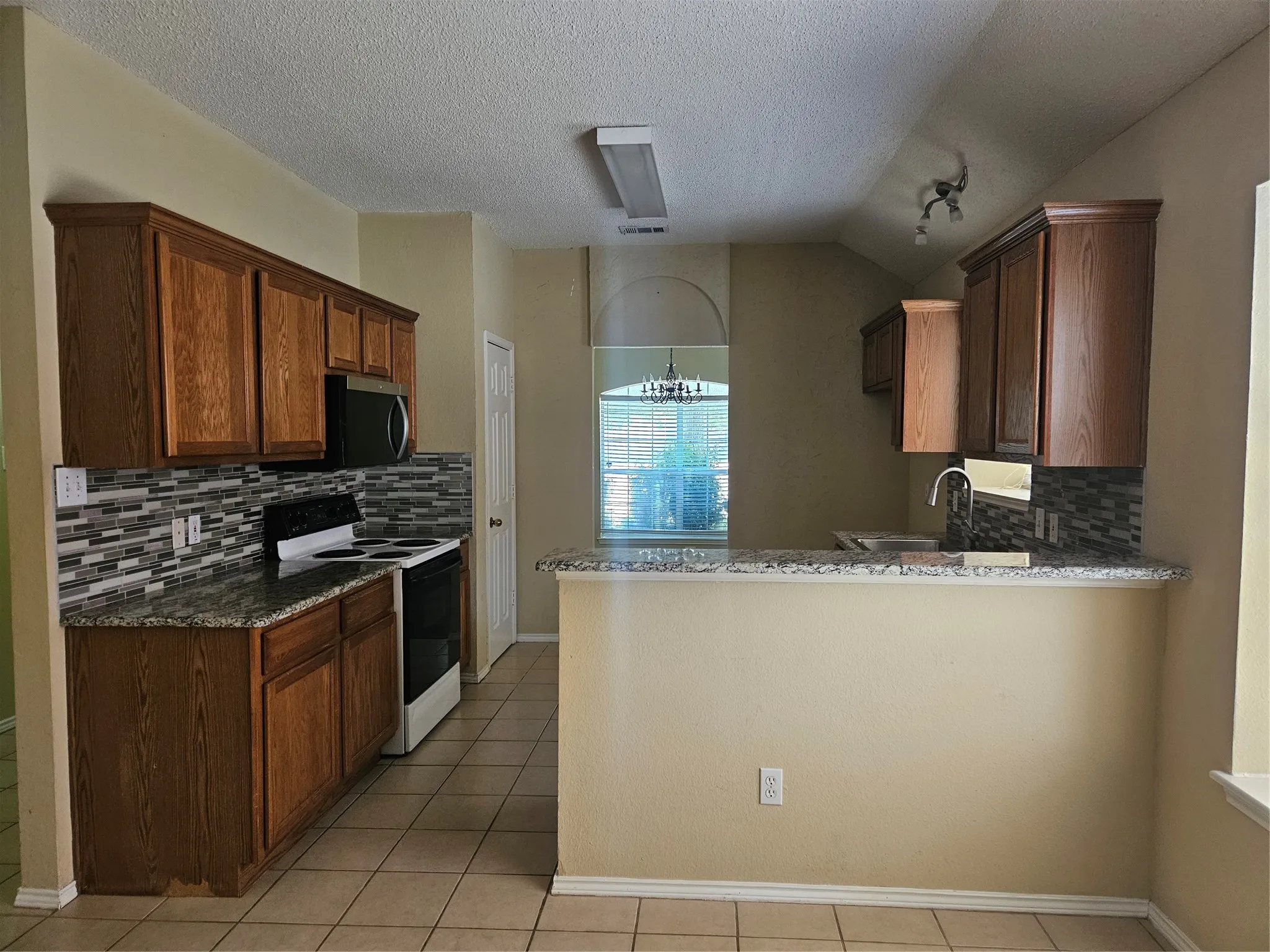 Wood-finish cabinetry, granite-style countertops, and a tiled backsplash