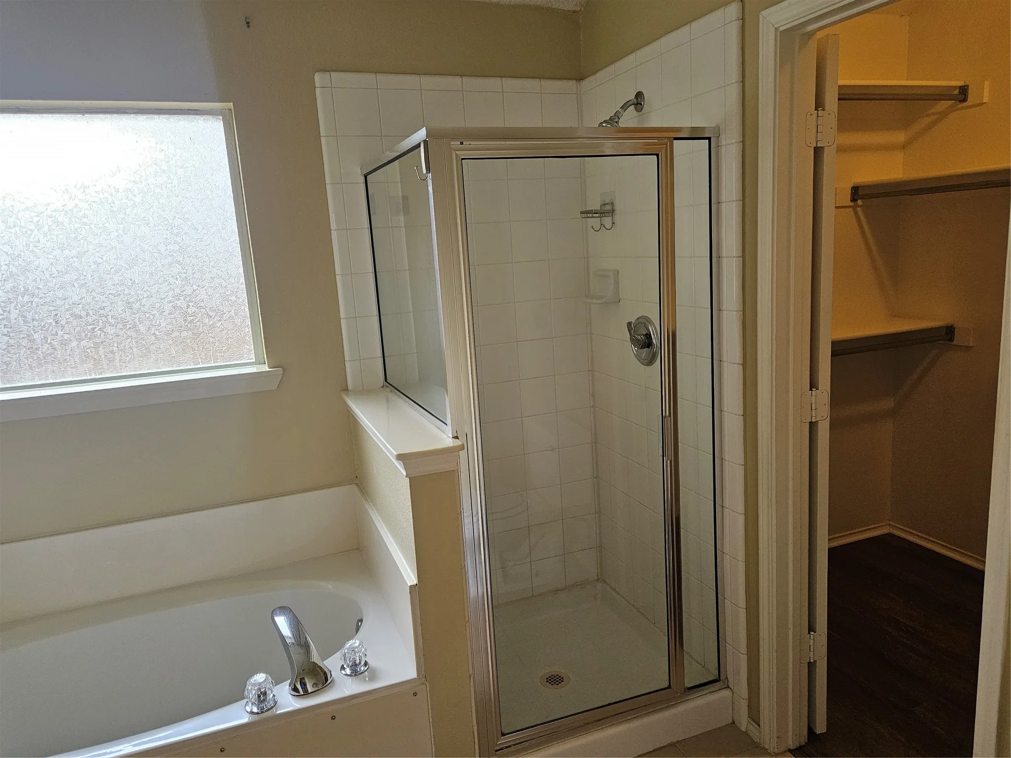 Tiled shower with glass enclosure, separate soaking tub, and a privacy window