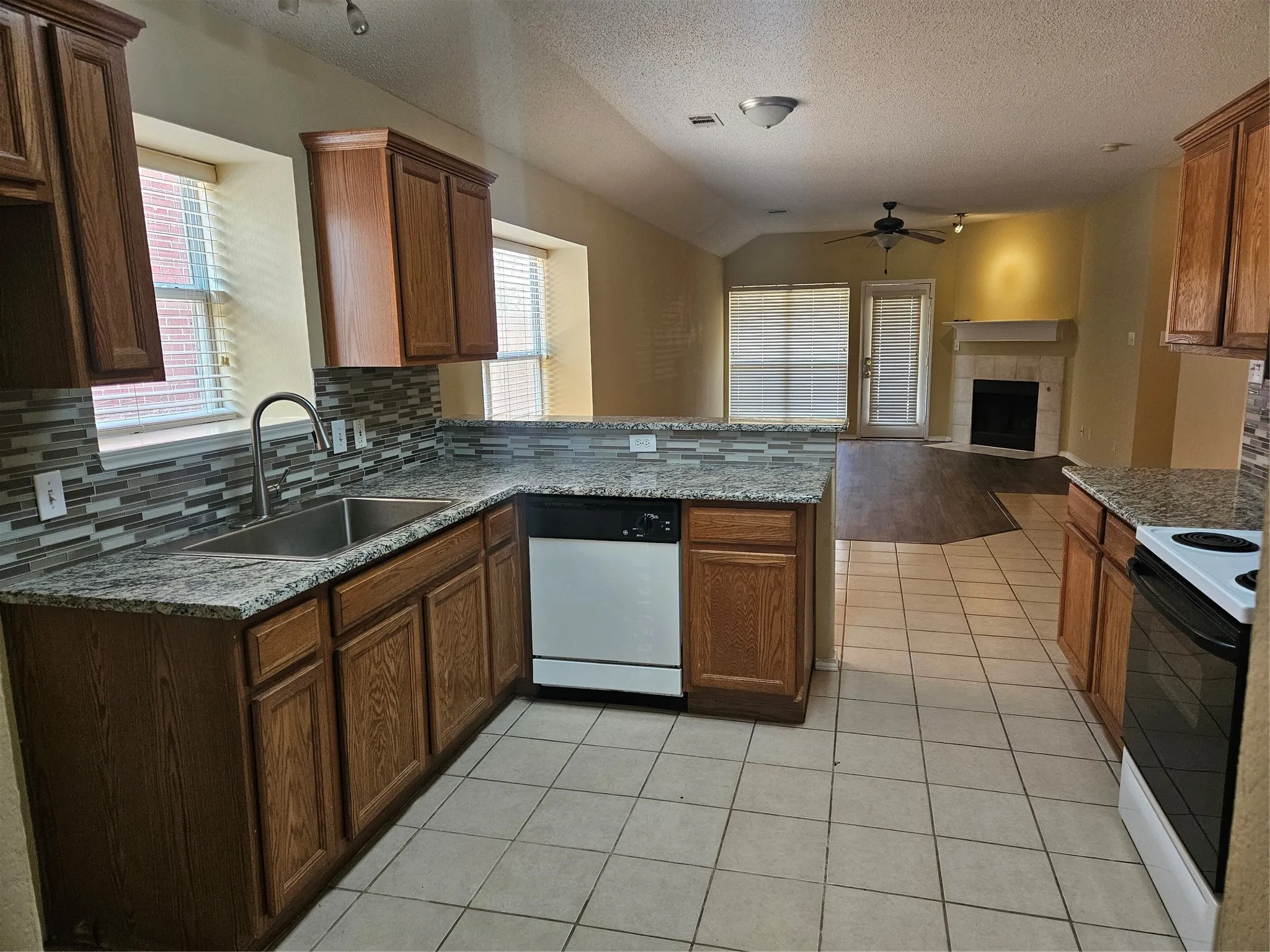 Kitchen with tile flooring, wood cabinetry, stone countertops, and a tile backsplash