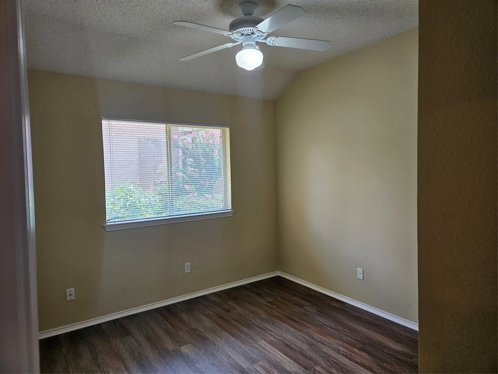 Vaulted ceiling with a ceiling fan, window with horizontal blinds, and wood-finish flooring
