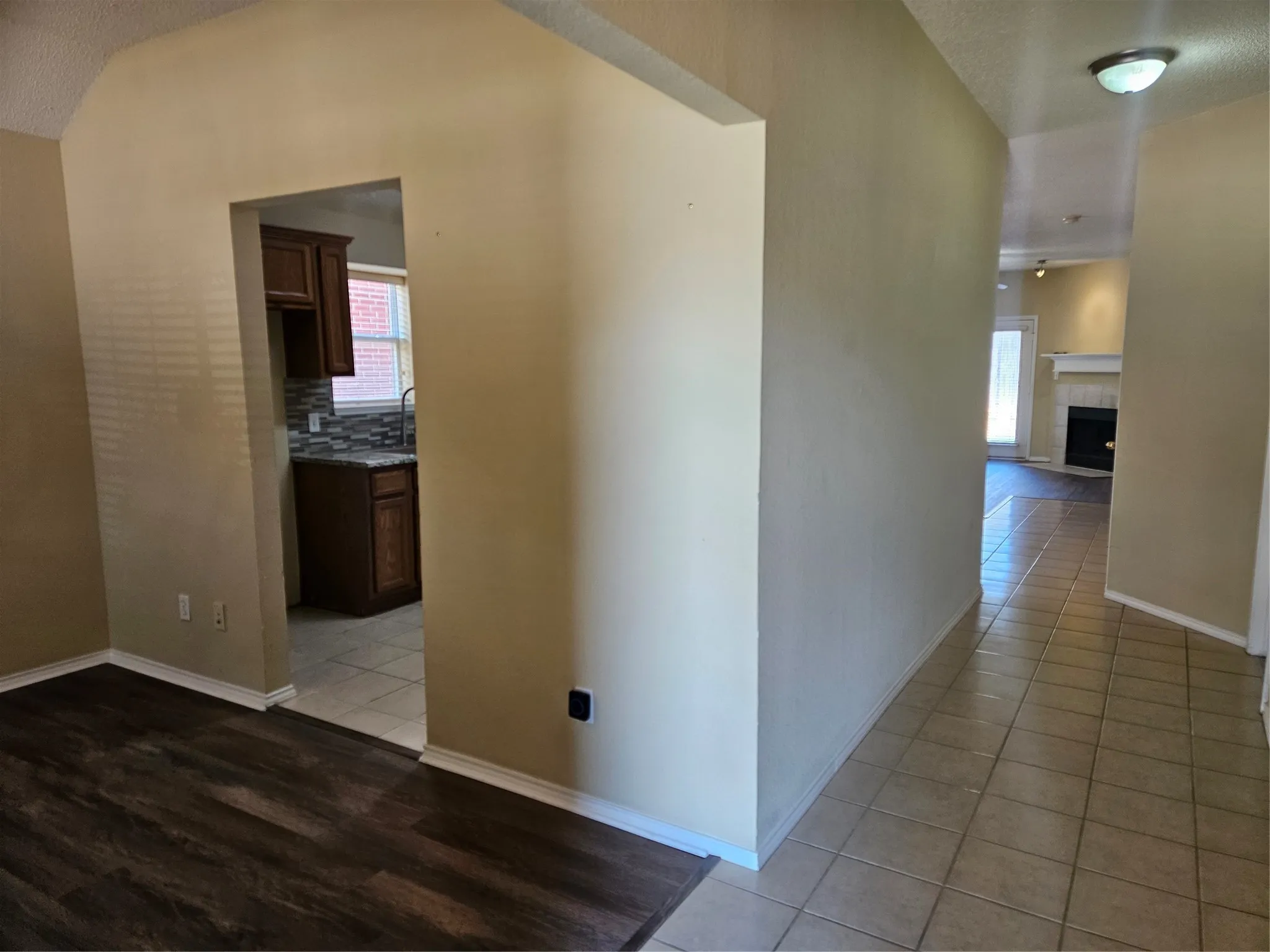 Wood-finish flooring, tiled flooring, wood cabinetry, tiled backsplash, and a fireplace with mantle