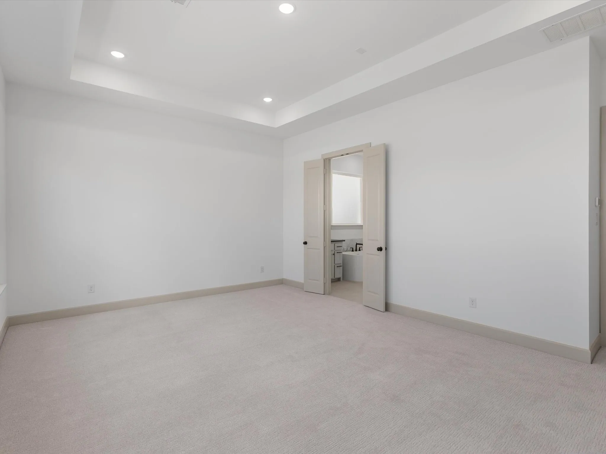 Primary Bedroom features Recessed lighting illuminating a tray ceiling, expansive windows, light-toned carpeting, and a neutral wall palette