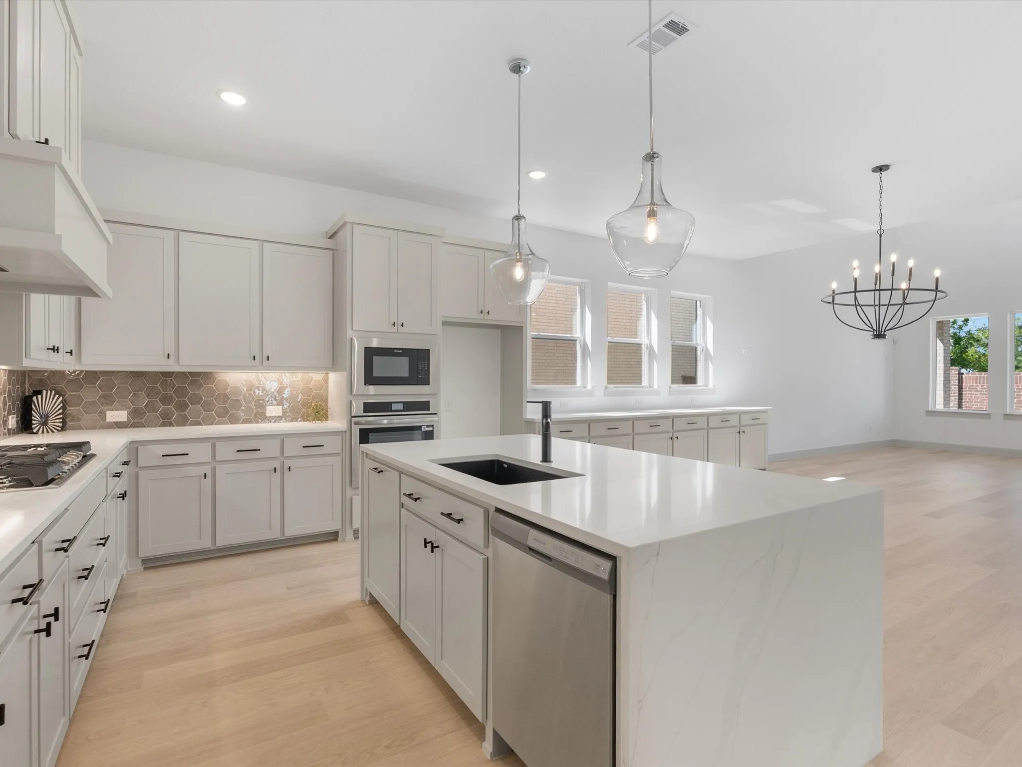Kitchen featuring an expansive center island with an undermount sink, stainless steel dishwasher, and quartz countertop