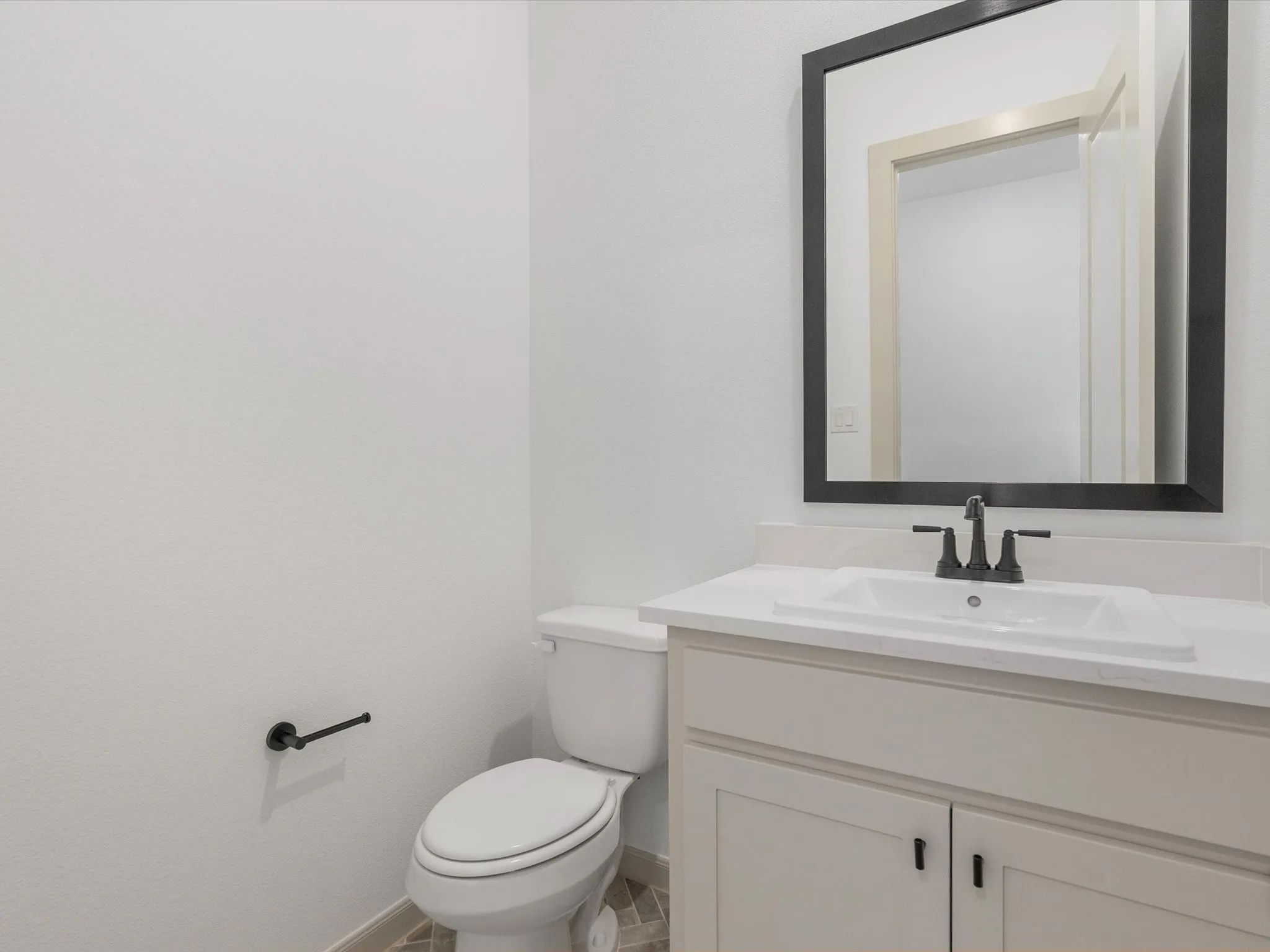 Half Bath Downstairs displays a White vanity with a rectangular integrated sink, black faucet, and framed mirror