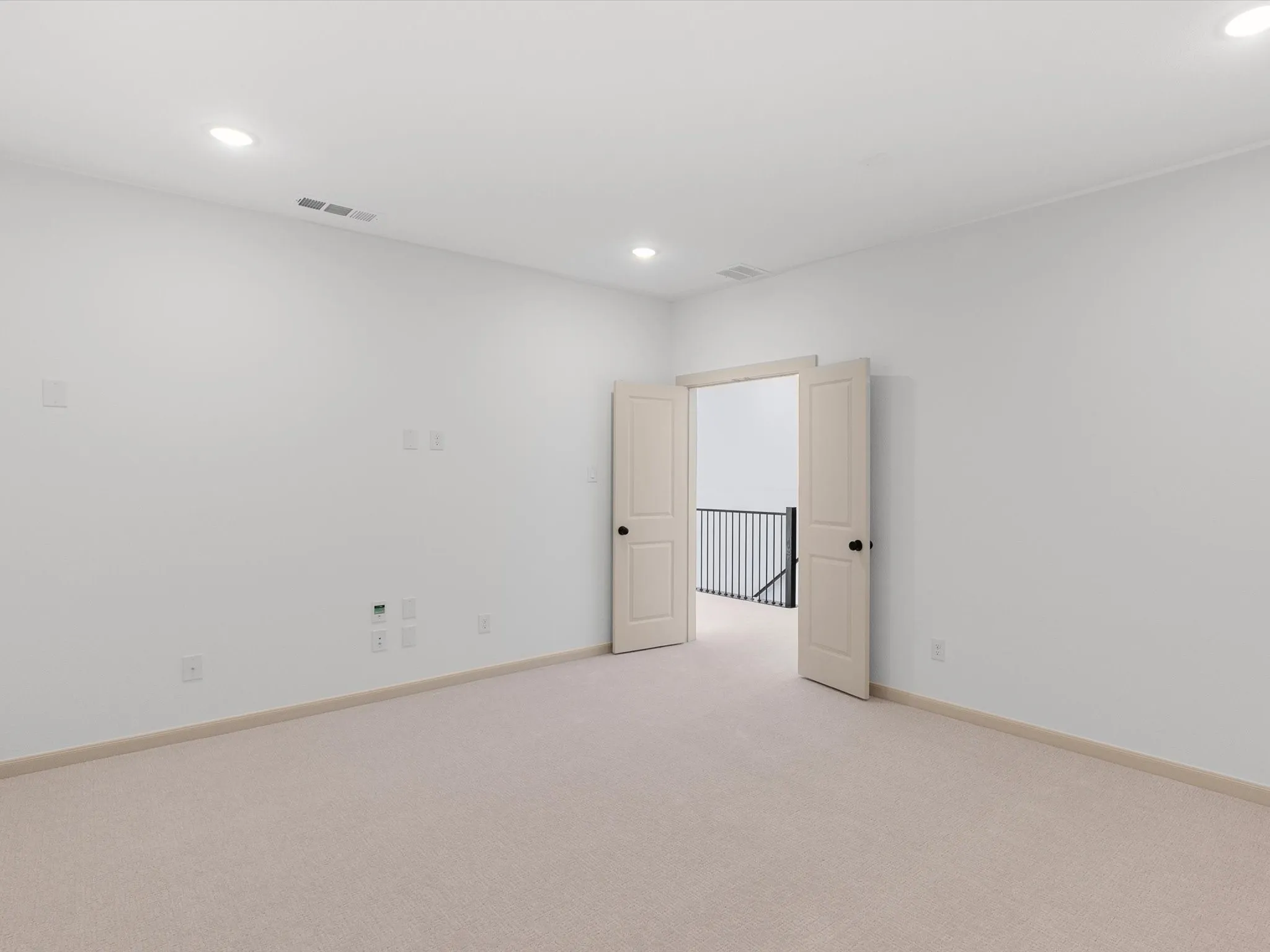 Recessed ceiling lighting, light-toned carpeting, neutral wall color, double entry doors