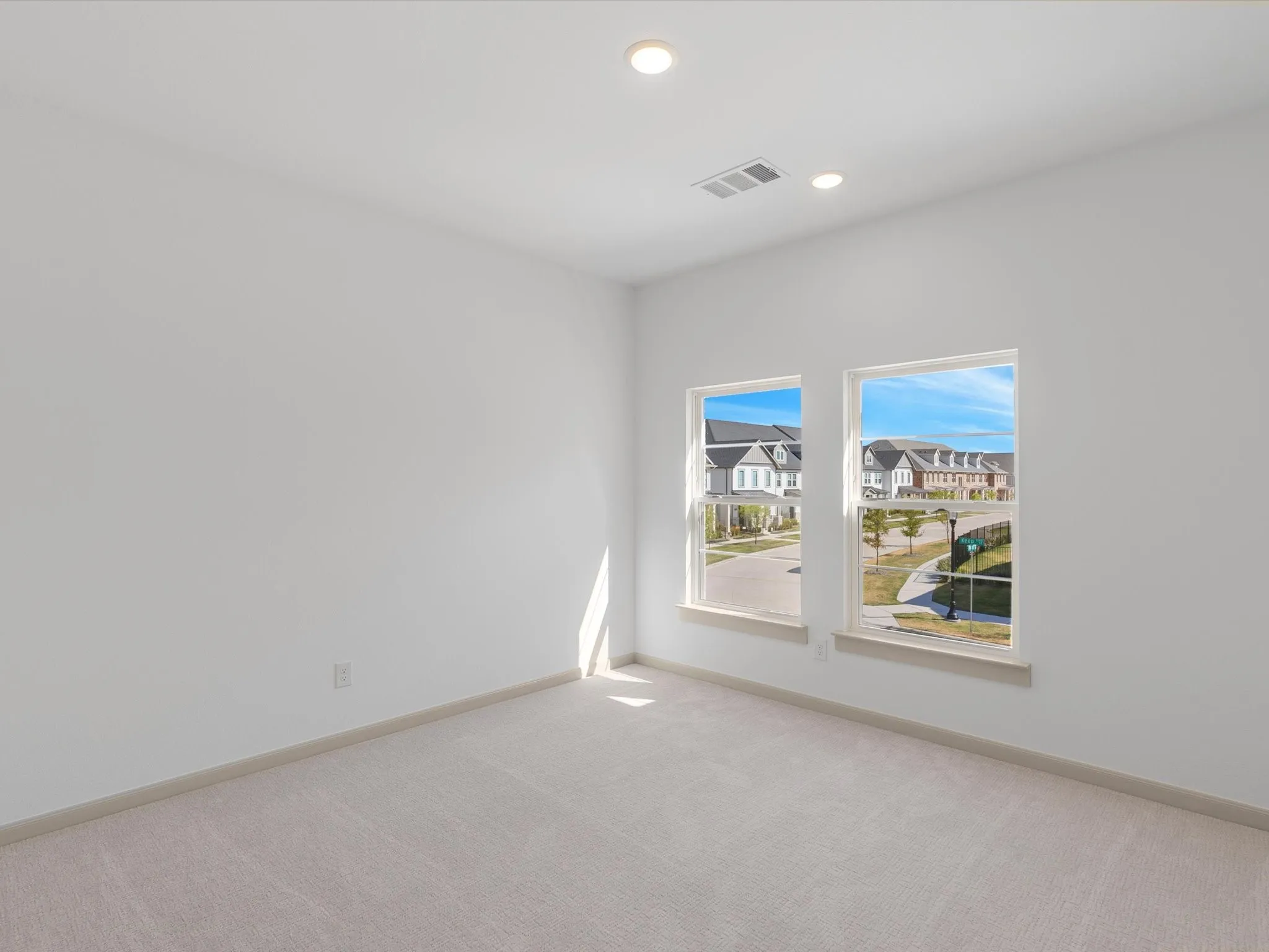 Recessed lighting, light-toned carpeting, white walls, and two windows with white trim