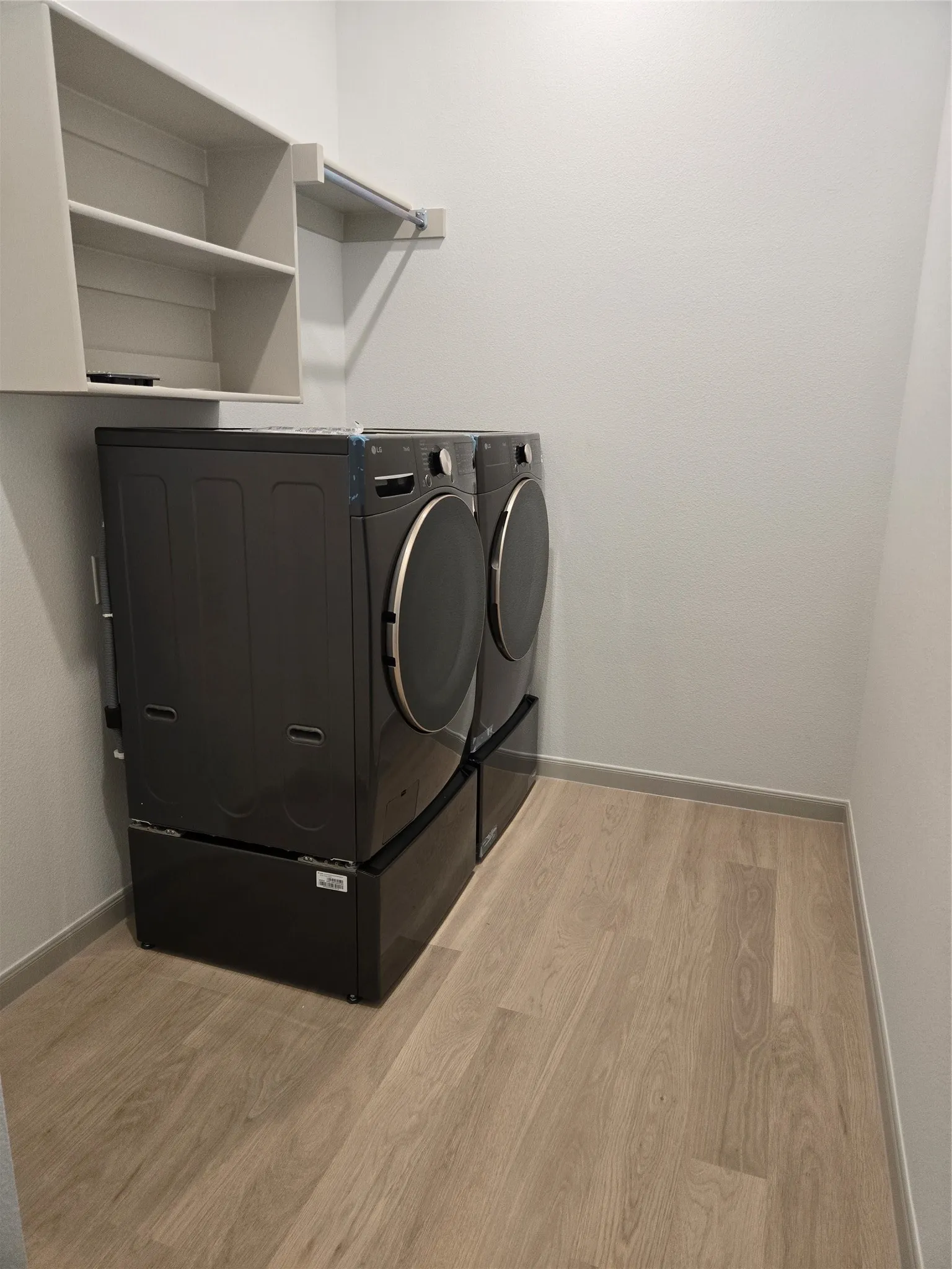 Dedicated laundry area featuring wood-finish flooring, built-in shelving, and a hanging rod