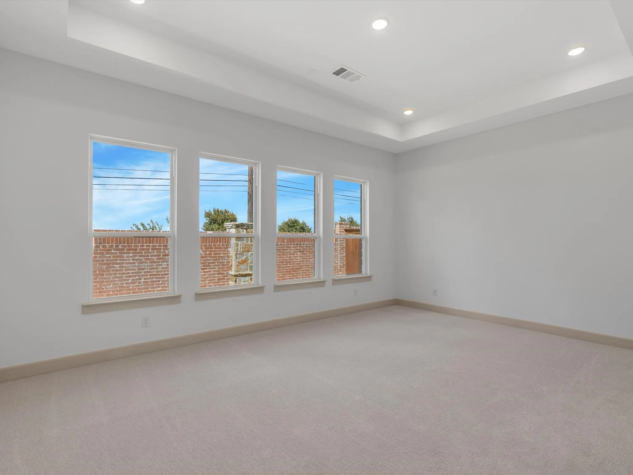 Primary Bedroom features Recessed lighting illuminating a tray ceiling, expansive windows, light-toned carpeting, and a neutral wall palette