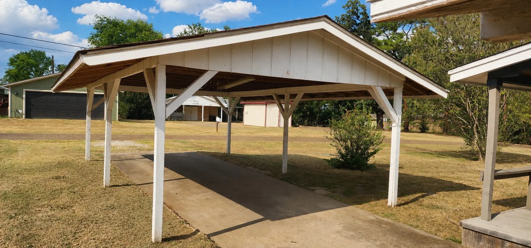 Covered carport with a concrete driveway and exposed wood rafter ceiling