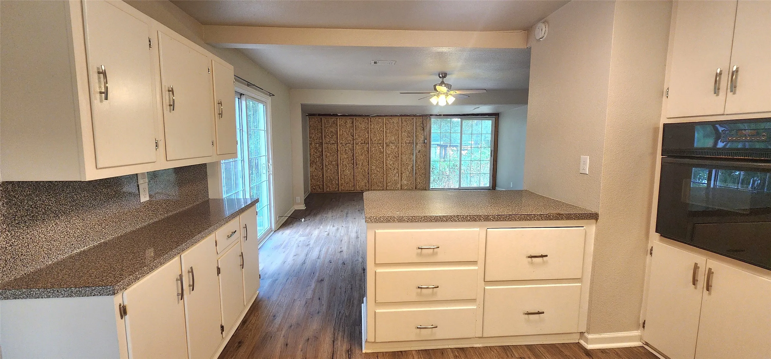 Kitchen featuring white cabinetry with silver-tone hardware, a built-in oven, and a peninsula with countertop seating