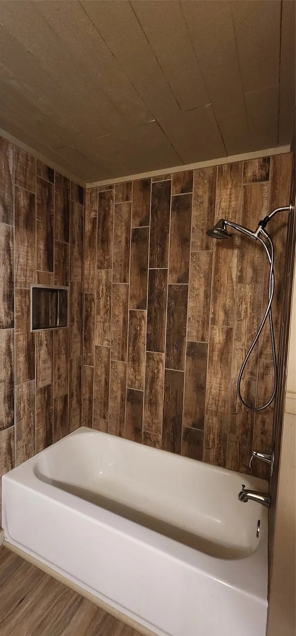 Tub/shower combination featuring wood-look tile surround and integrated shower niche