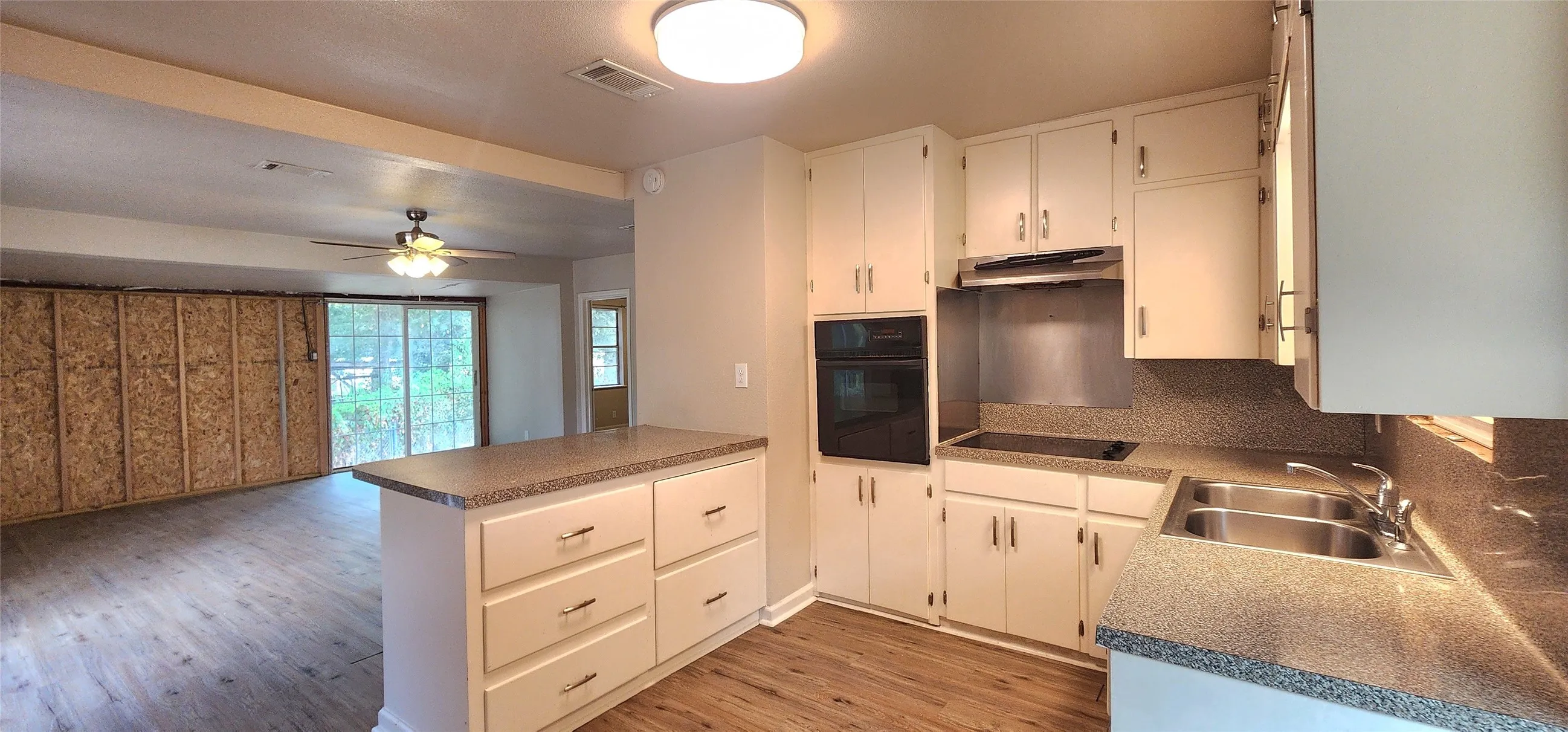 Kitchen featuring white cabinetry, built-in double ovens, a flat-top electric range, a double basin stainless steel sink, and vinyl flooring