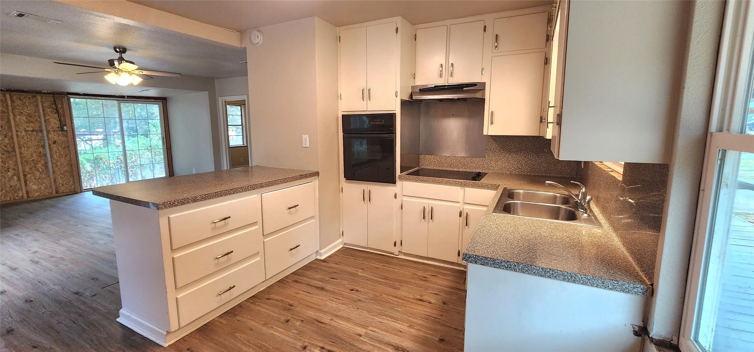 Kitchen with white cabinetry, built-in oven, integrated cooktop, double basin sink, and vinyl flooring