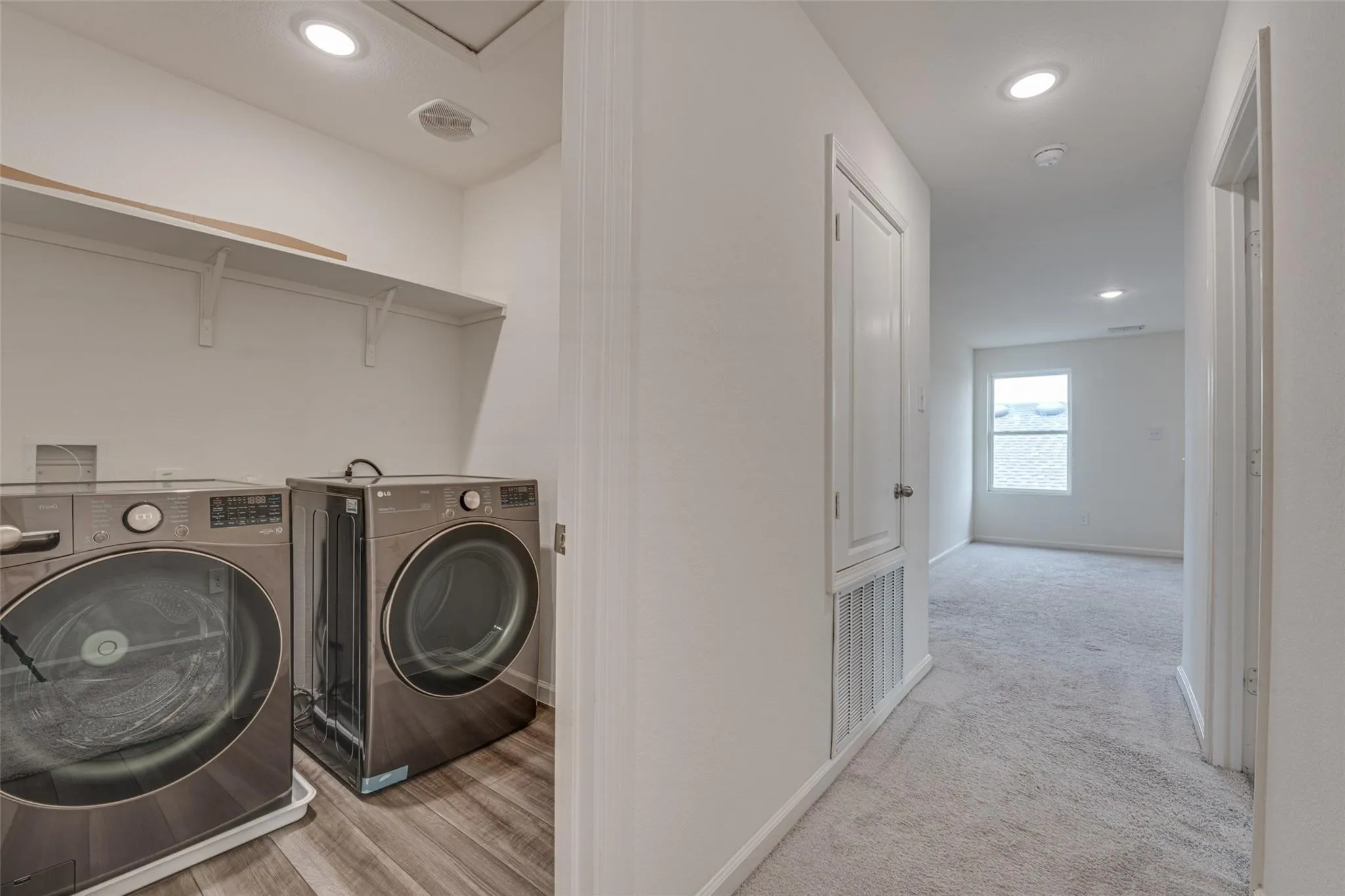 Dedicated laundry area with wood-finish flooring and built-in shelving