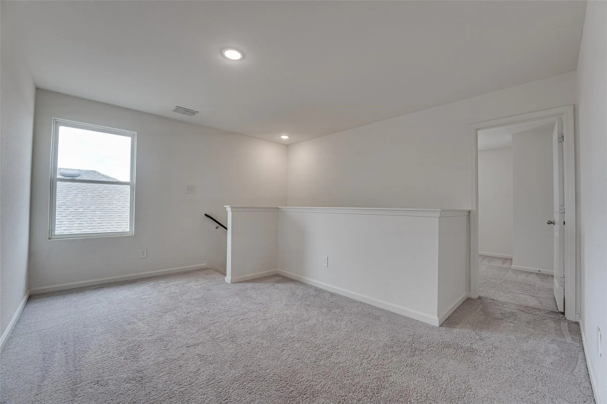 Light gray carpeting, white painted walls, recessed lighting, and a white interior door