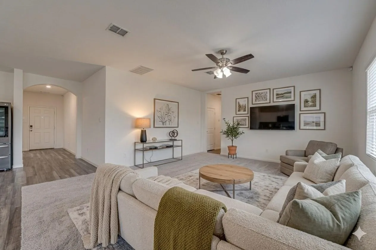 Spacious open-concept living area featuring a ceiling fan, arched doorway, and wood-finish flooring