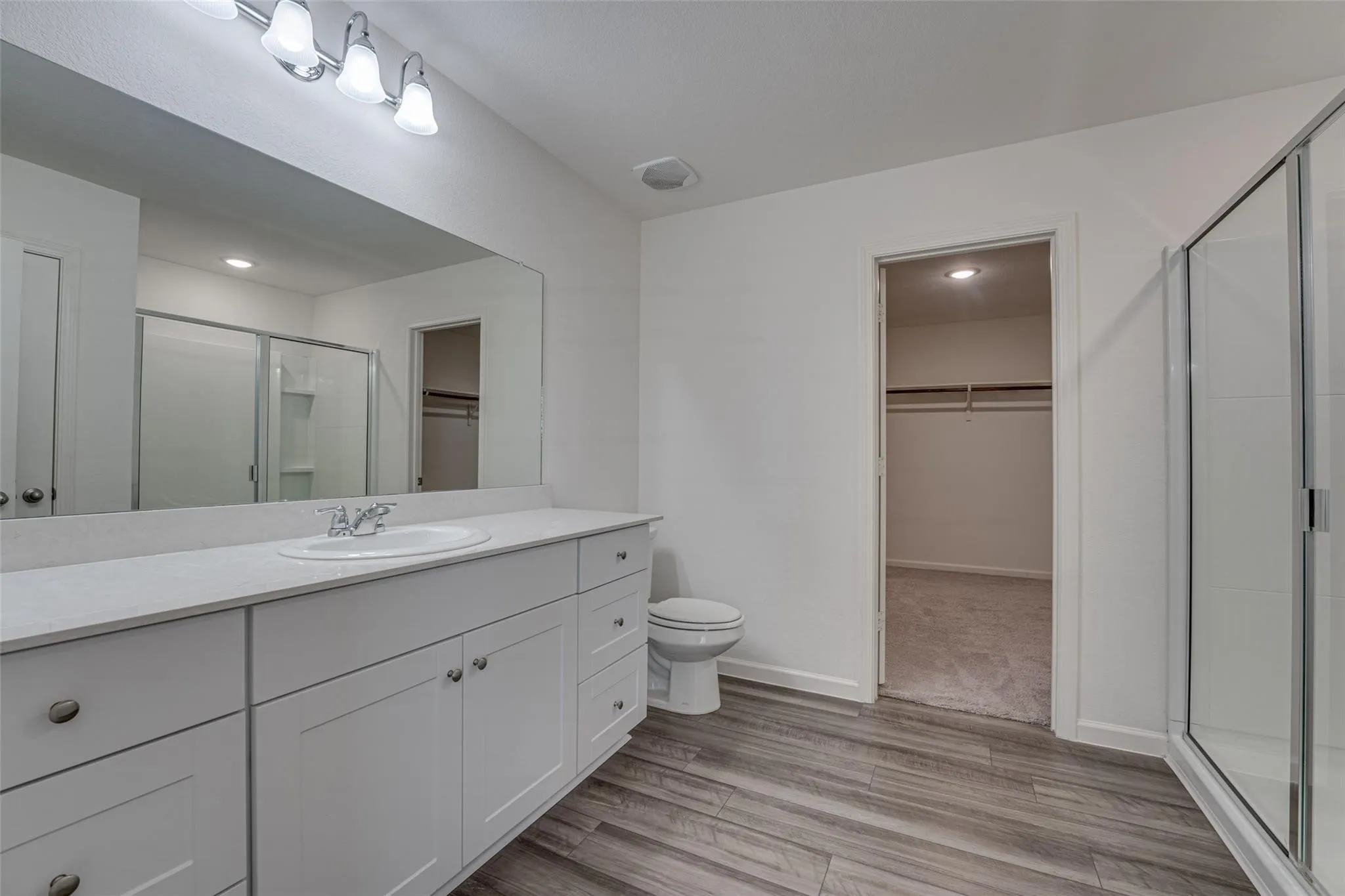Bathroom featuring a white vanity with extensive counter space, an integrated sink, and white cabinetry