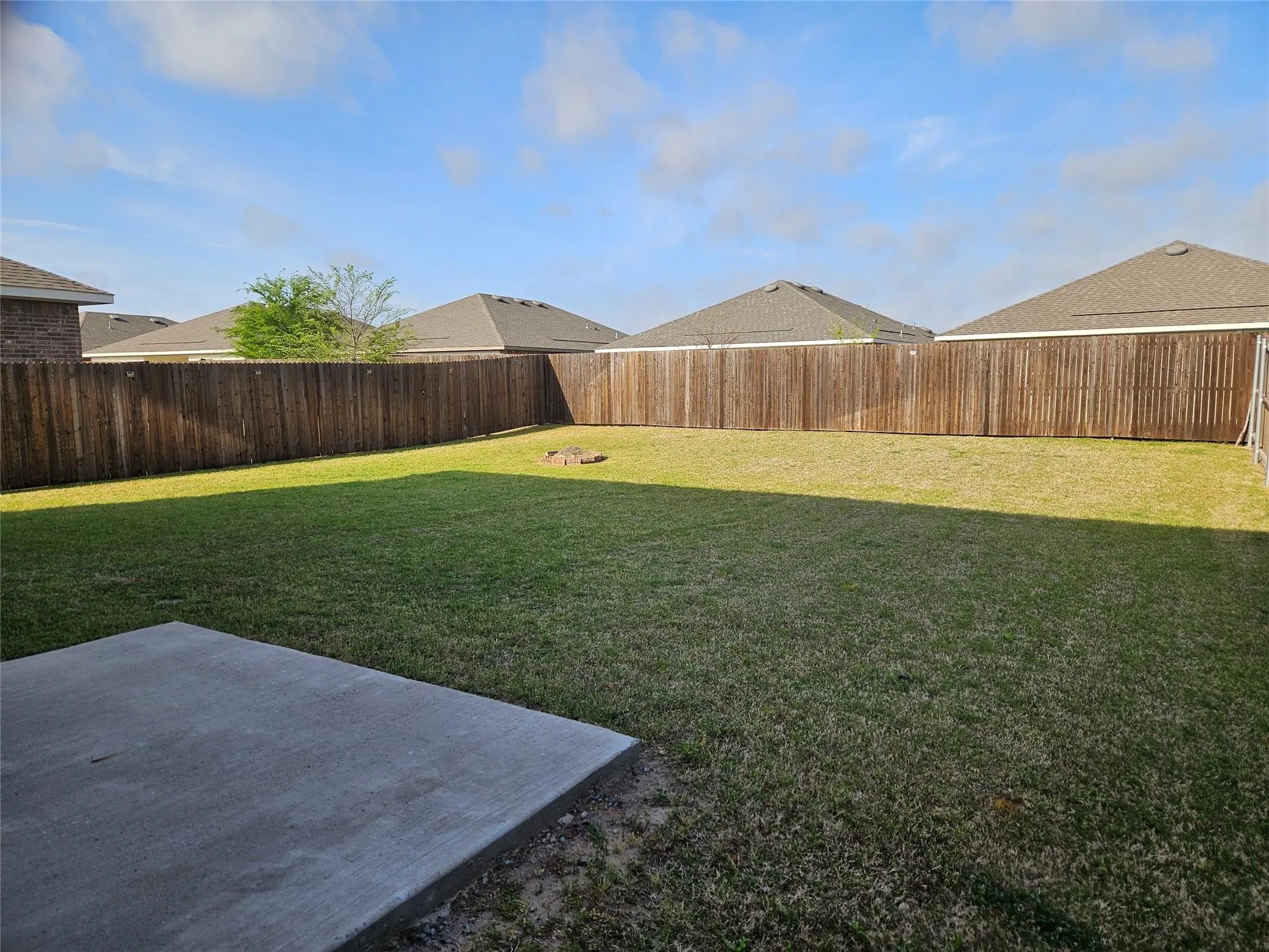 Expansive fenced backyard featuring a large concrete patio and mature wood privacy fencing