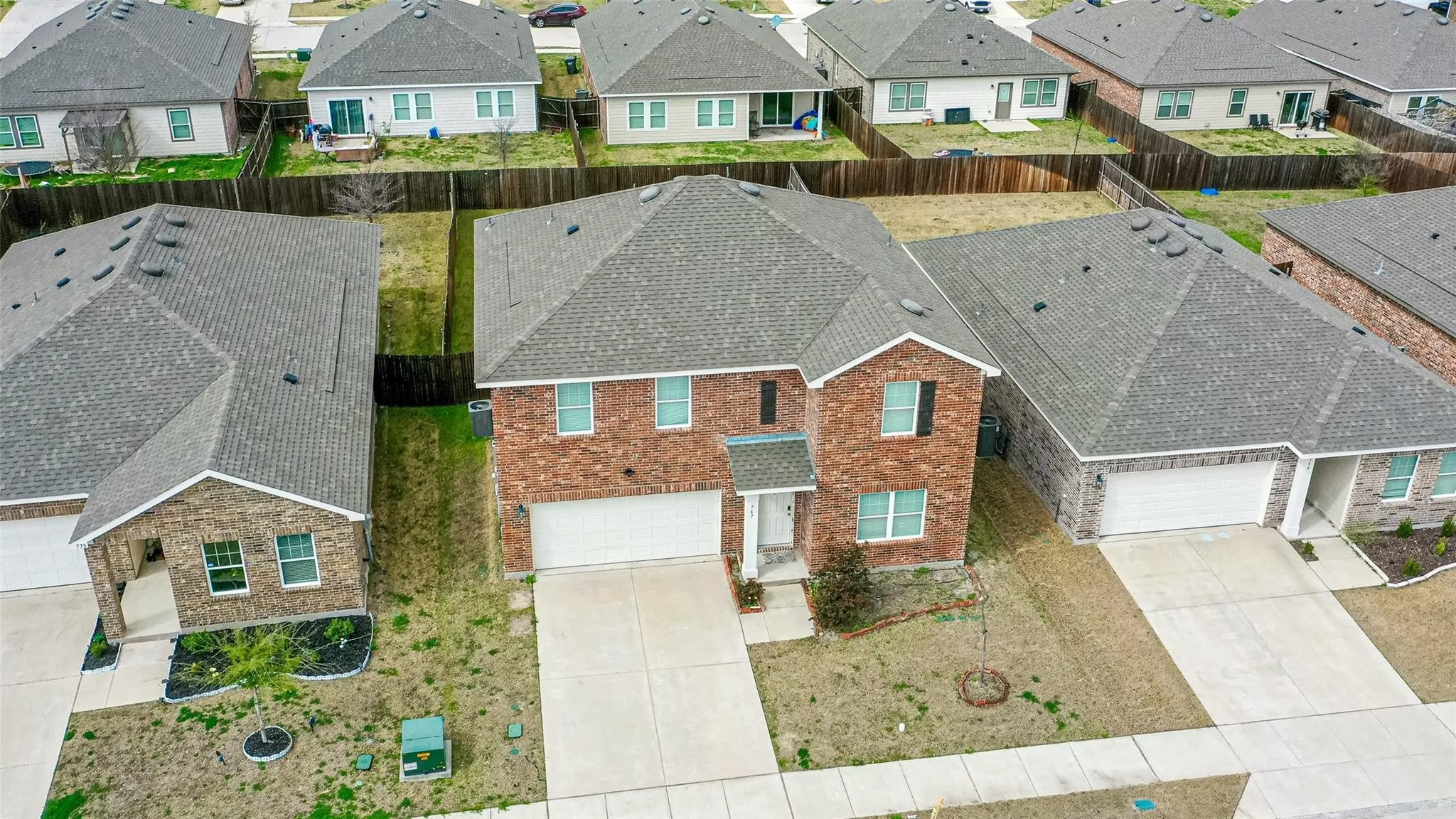 Two-story brick facade residence with an attached two-car garage, concrete driveway, and front landscaping