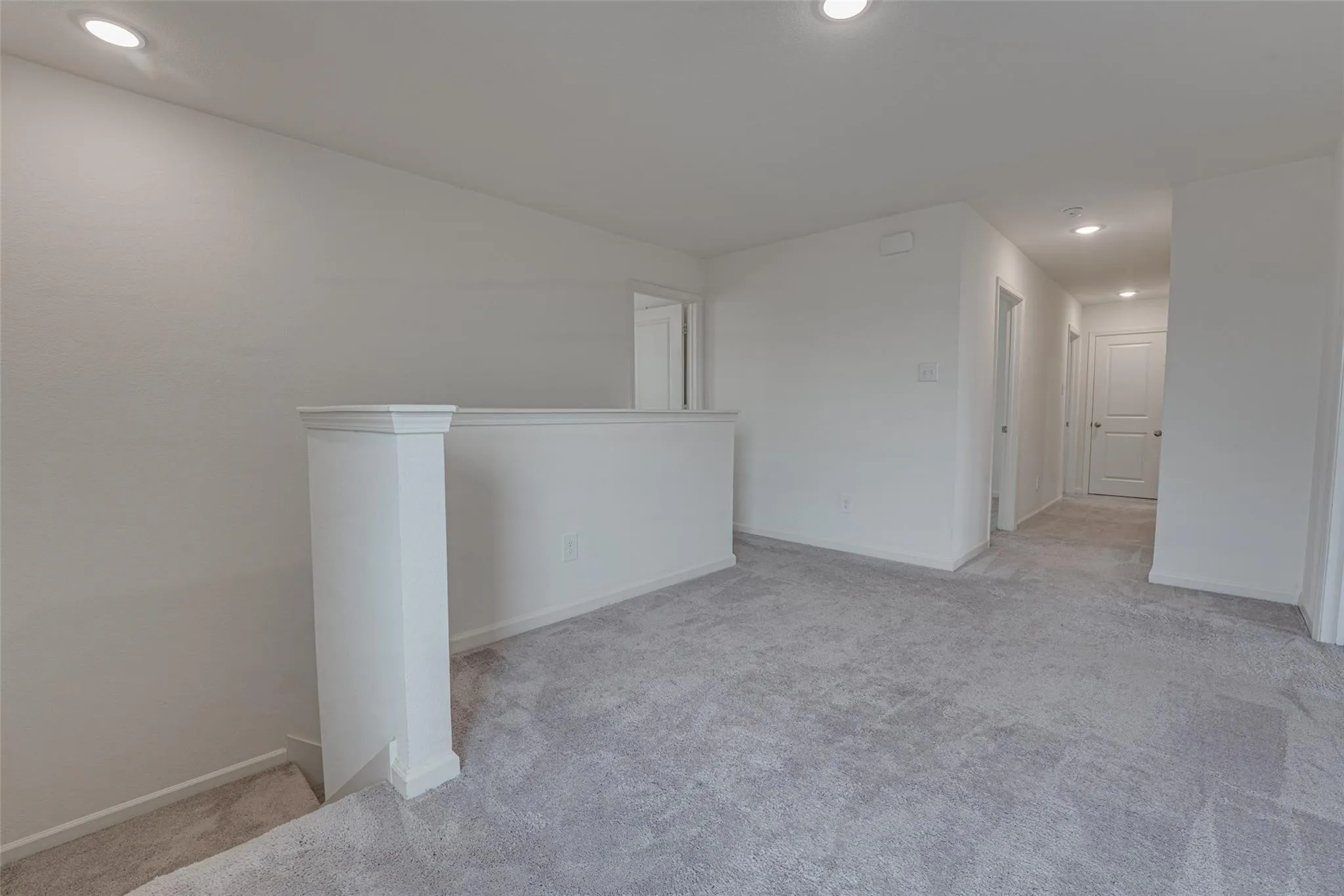 Carpeted landing with recessed lighting and painted walls