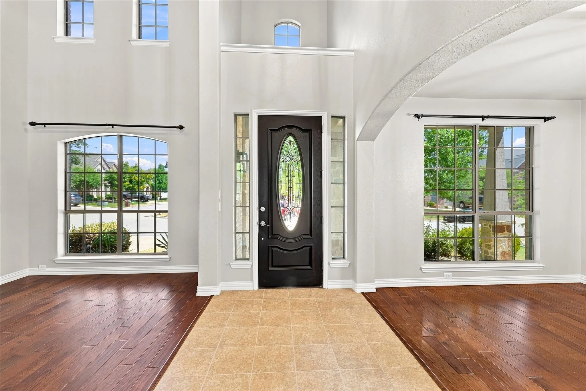 Two-story entryway with a dark wood-finish door featuring an oval leaded glass insert and sidelights