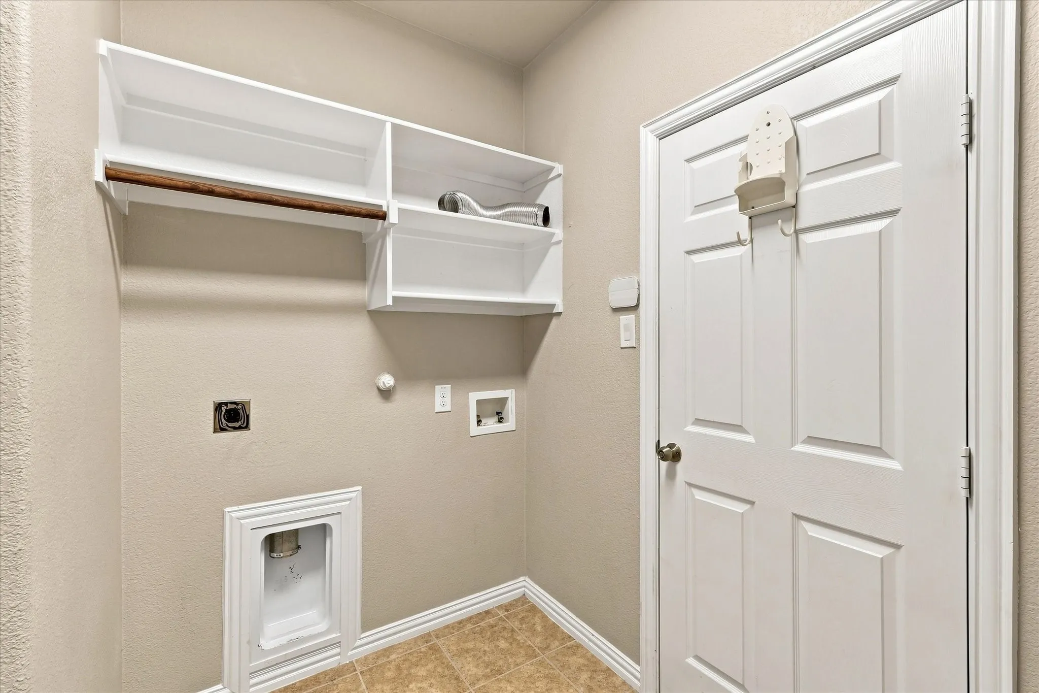 Laundry area featuring overhead shelving, a hanging rod, and a paneled door
