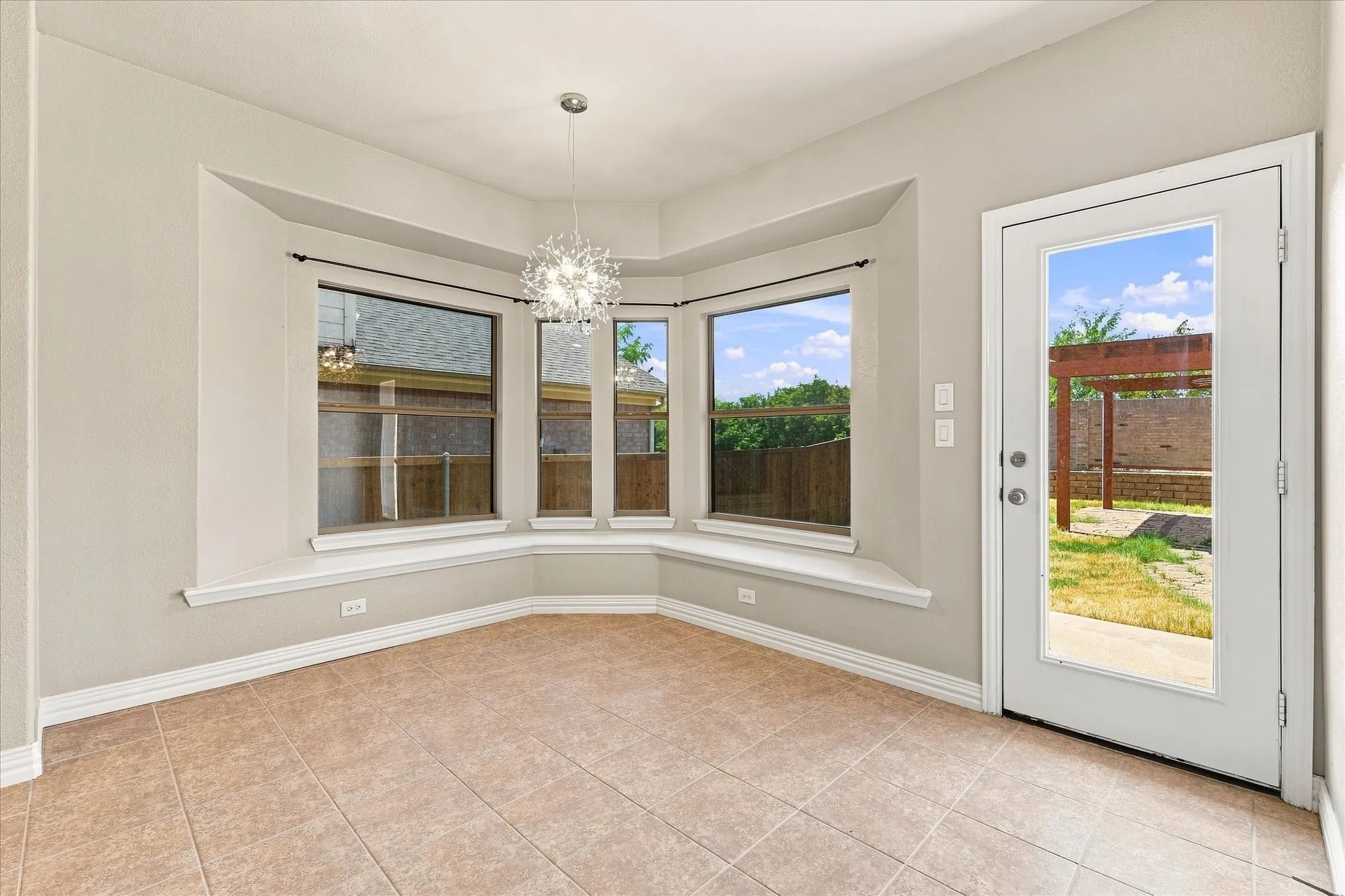 Tiled flooring, bay window with integrated sill, pendant light fixture, and a glass-paneled exterior door