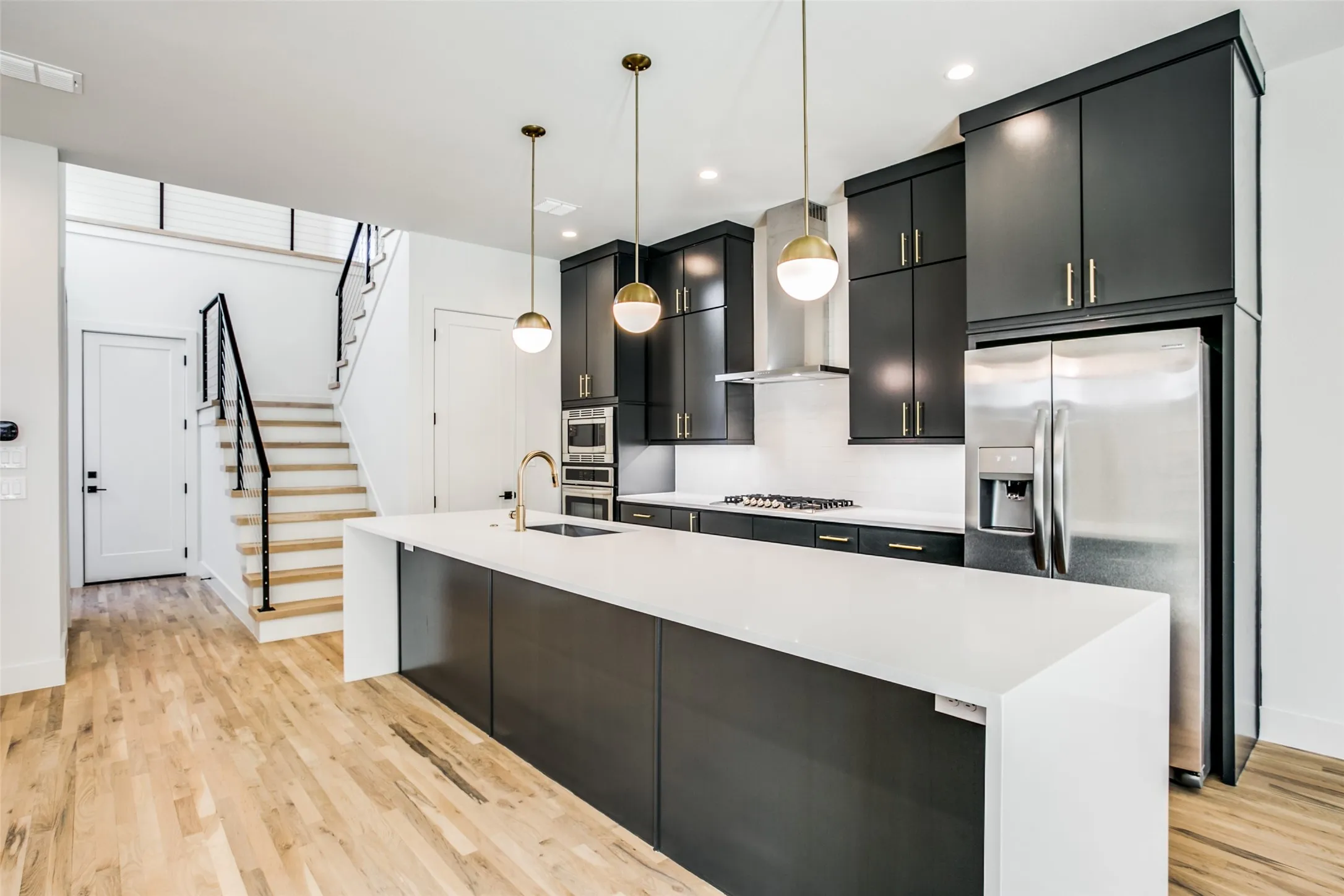 This photo reveal the door from garage into entry and the white oak floors and stairs.