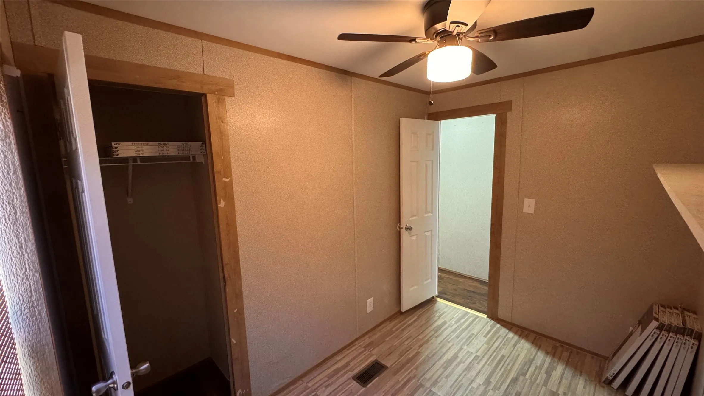Wood-finish flooring, ceiling fan with integrated lighting, and a closet with wire shelving