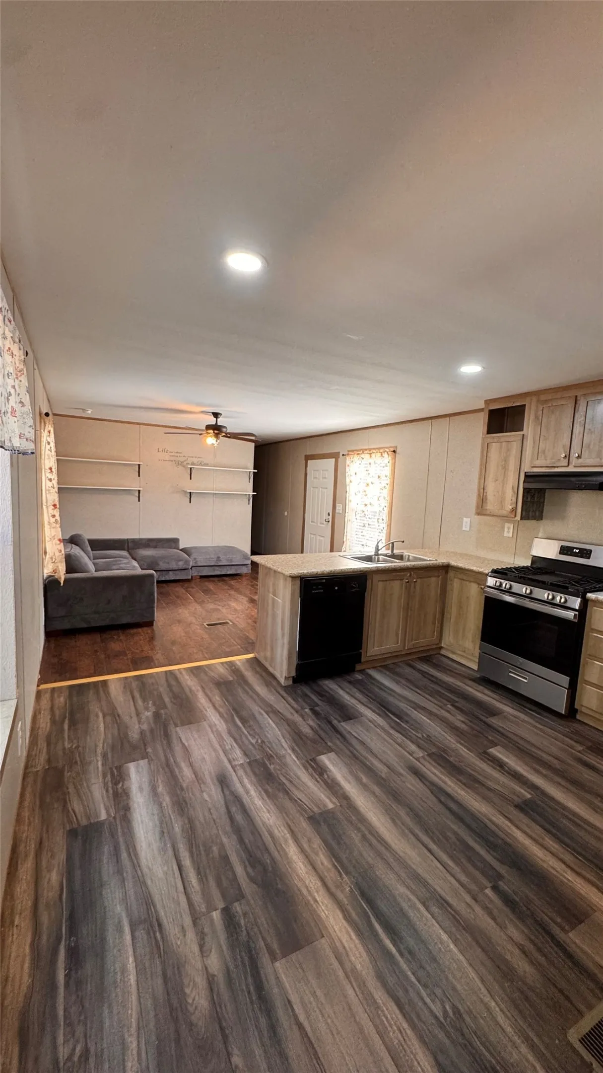 Open-concept living space featuring wood-finish flooring, recessed lighting, and a ceiling fan